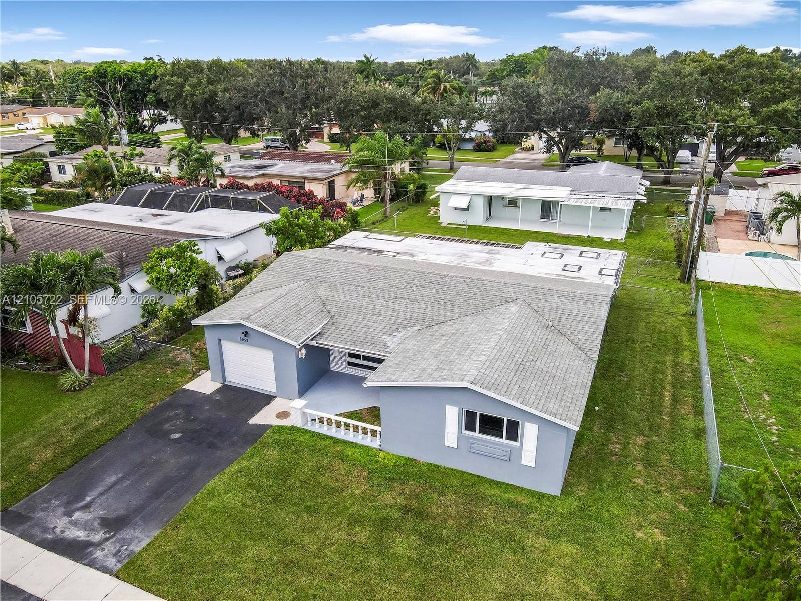 8953 SW 53rd Street, Cooper City, FL 33328 Single-story residence featuring a painted exterior, attached one-car garage, front porch with a decorative balustrade, and a manicured lawn