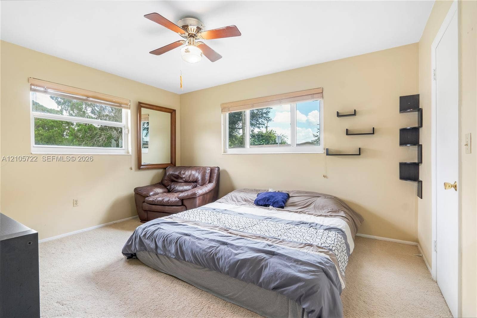 8953 SW 53rd Street, Cooper City, FL 33328 Dual windows providing natural light, central ceiling fan with integrated lighting, neutral wall color, and wall-mounted shelving