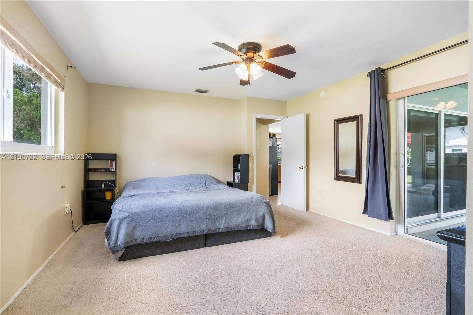 8953 SW 53rd Street, Cooper City, FL 33328 Neutral-toned interior room featuring wall-to-wall carpeting, ceiling fan with integrated lighting, and a large sliding glass door