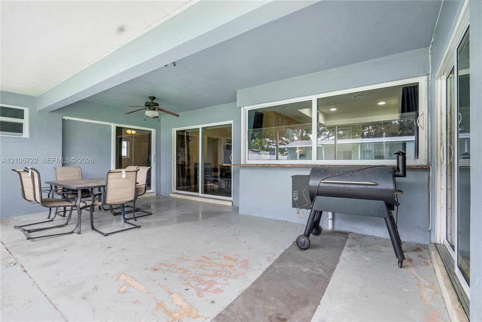 8953 SW 53rd Street, Cooper City, FL 33328 Covered patio featuring a concrete floor, built-in pass-through window with a stone-finish counter, and a ceiling-mounted fan