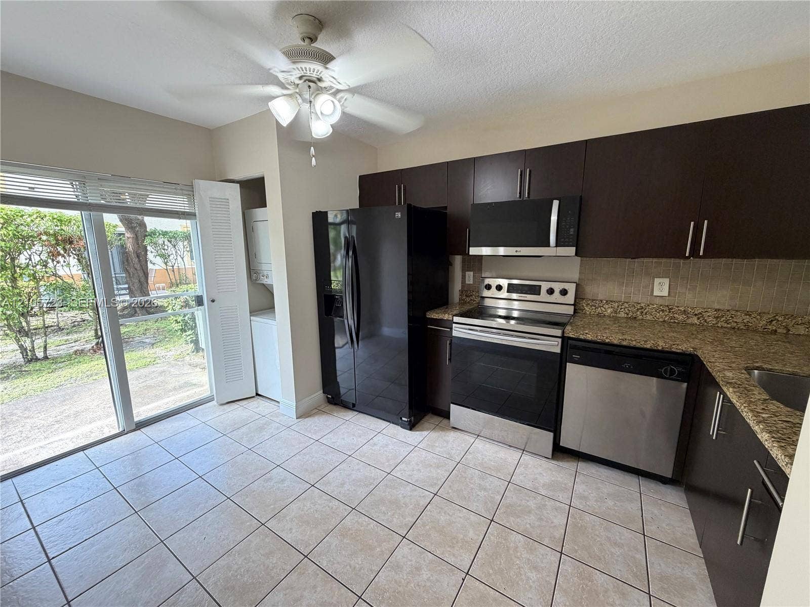 4785 SW 62nd Avenue, #102, Davie, Davie, FL 33314 Kitchen featuring dark cabinetry, stone-finish countertops, stainless steel appliances, tile flooring, and glass sliding doors