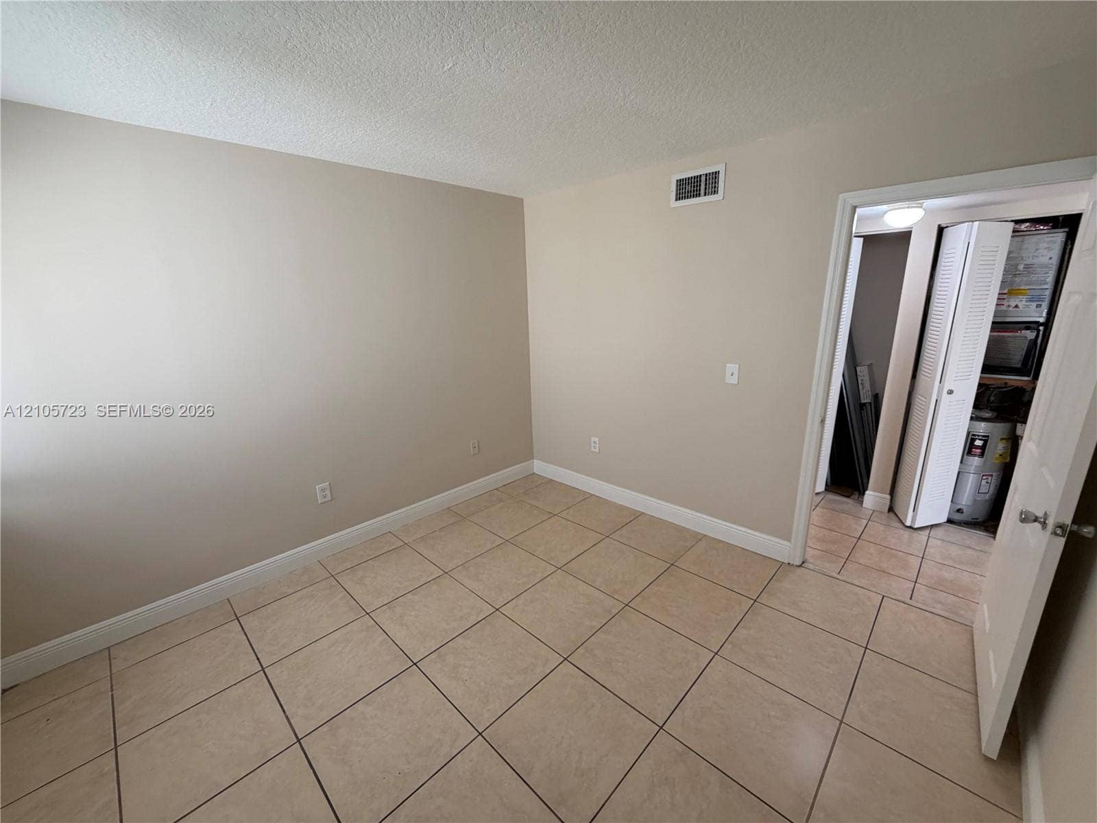 4785 SW 62nd Avenue, #102, Davie, Davie, FL 33314 Neutral-toned interior space featuring ceramic tile flooring, a six-panel interior door, and a folding-door closet