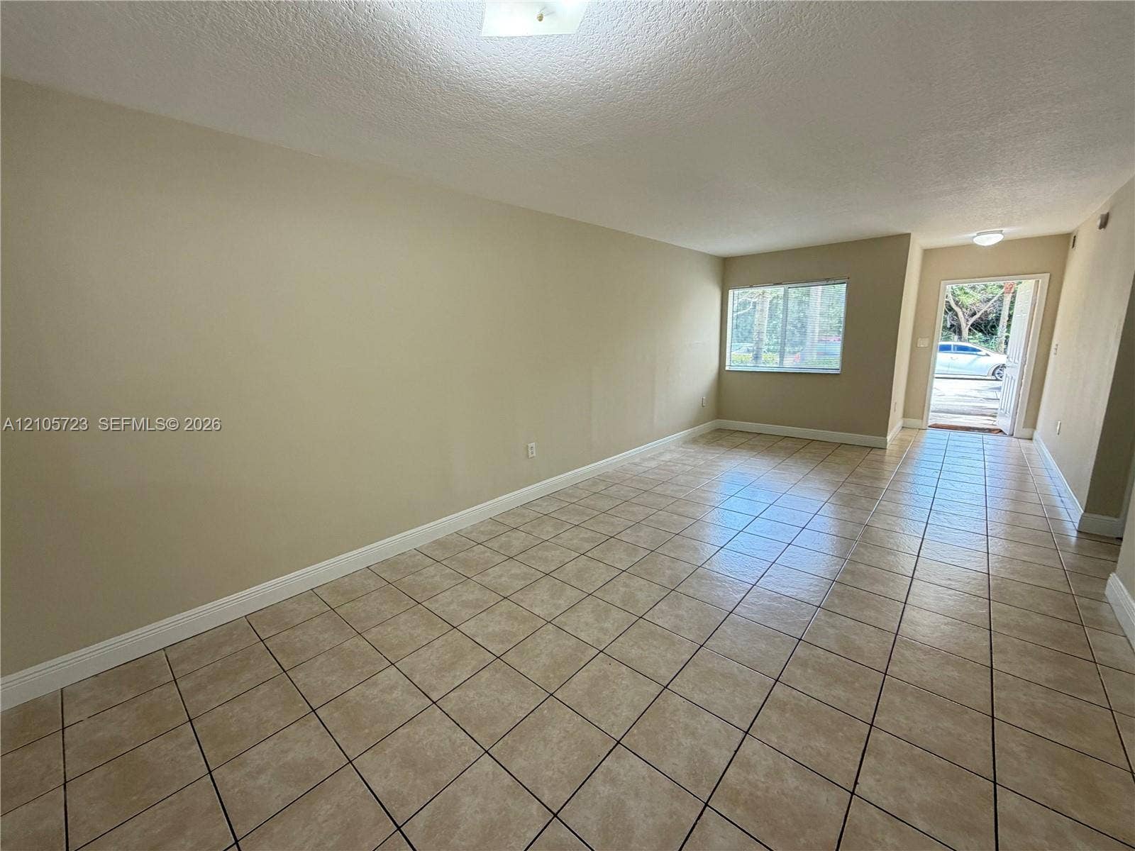 4785 SW 62nd Avenue, #102, Davie, Davie, FL 33314 Neutral-toned interior featuring ceramic tile flooring, textured ceiling, and natural light via sliding window