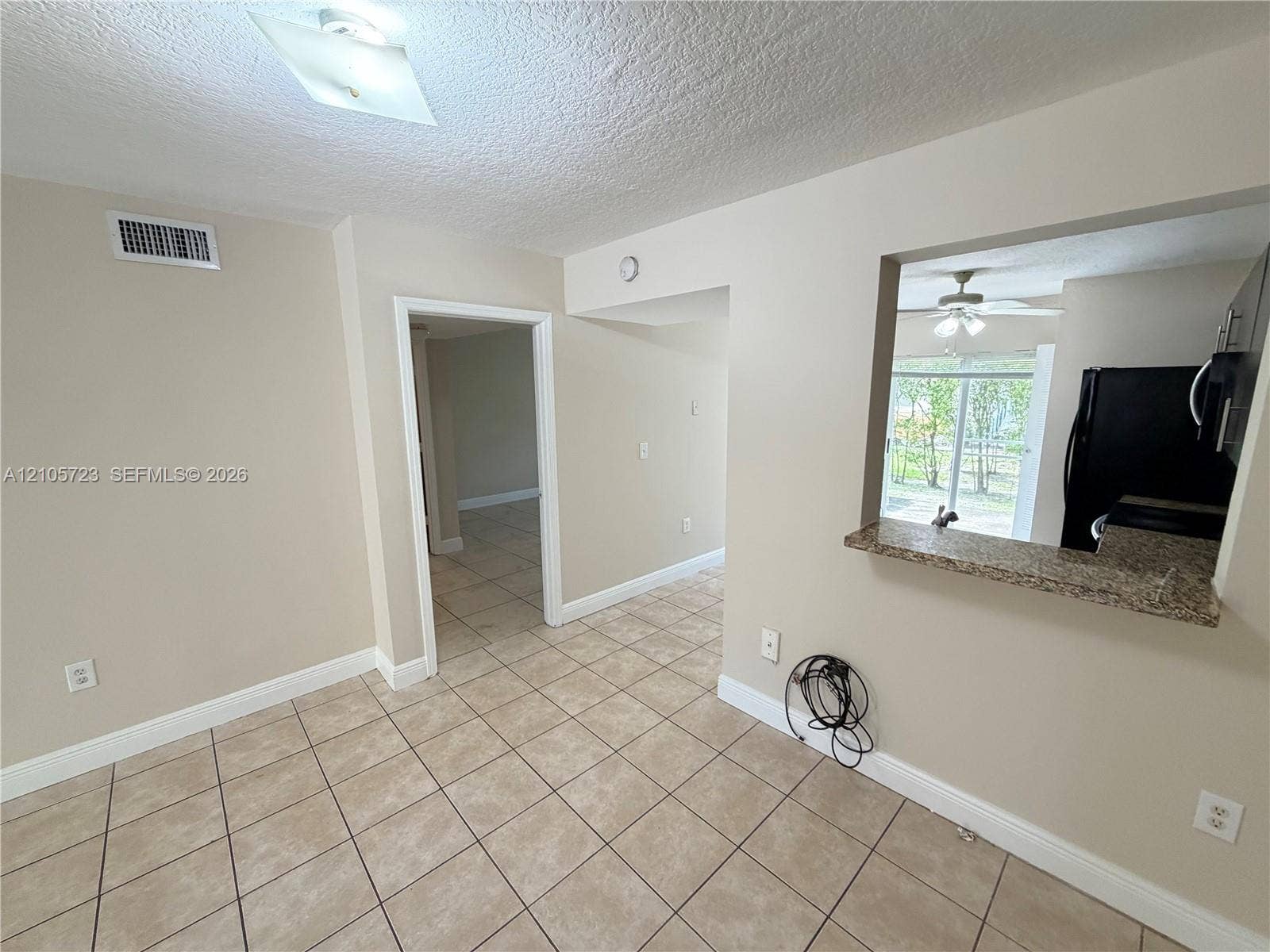 4785 SW 62nd Avenue, #102, Davie, Davie, FL 33314 Neutral-toned interior featuring ceramic tile flooring, a stone-surface pass-through counter, and a flush-mount ceiling light fixture