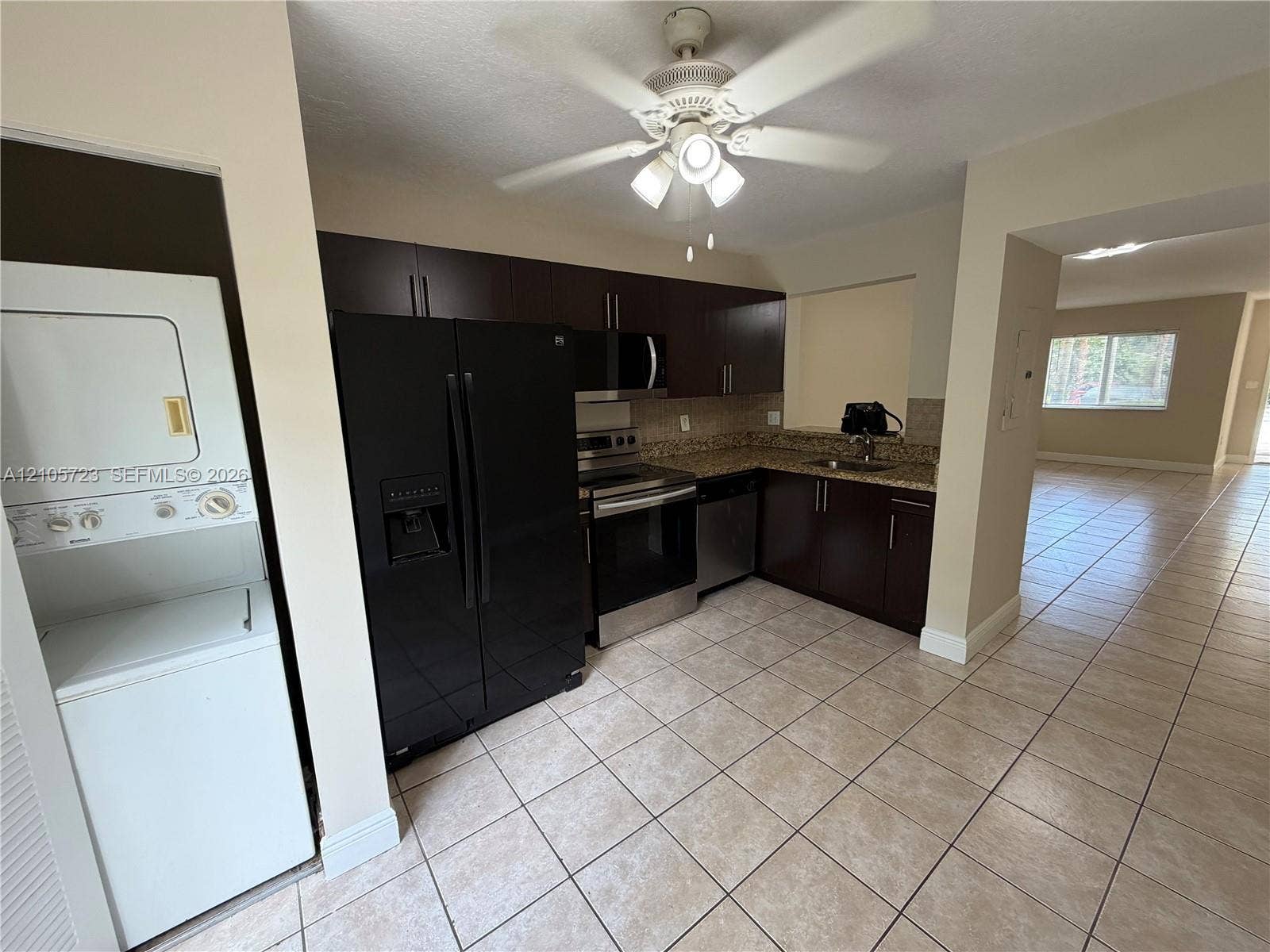 4785 SW 62nd Avenue, #102, Davie, Davie, FL 33314 Kitchen featuring dark wood-finish cabinetry, stone-style countertops, stainless steel appliances, a ceiling-mounted light fixture, and tile flooring