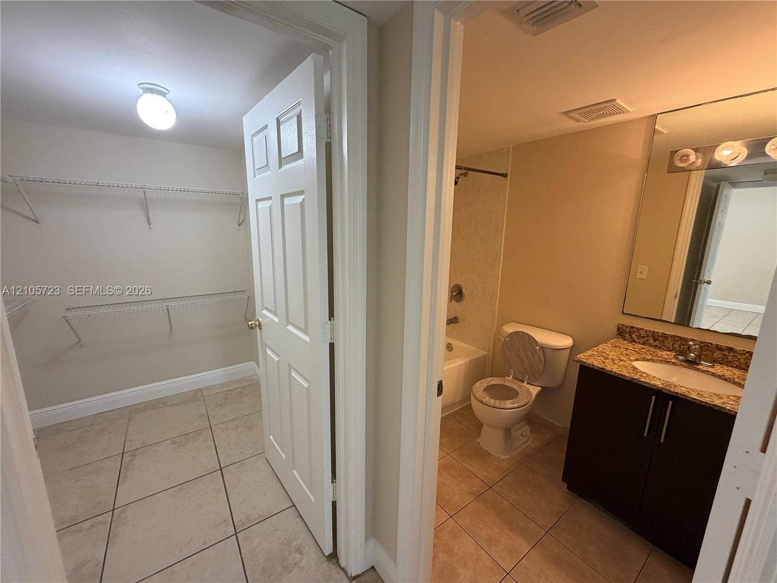 4785 SW 62nd Avenue, #102, Davie, Davie, FL 33314 Bathroom featuring tile flooring, dark wood-finish cabinetry, stone-surface countertop with an integrated basin, and a bathtub with a shower surround