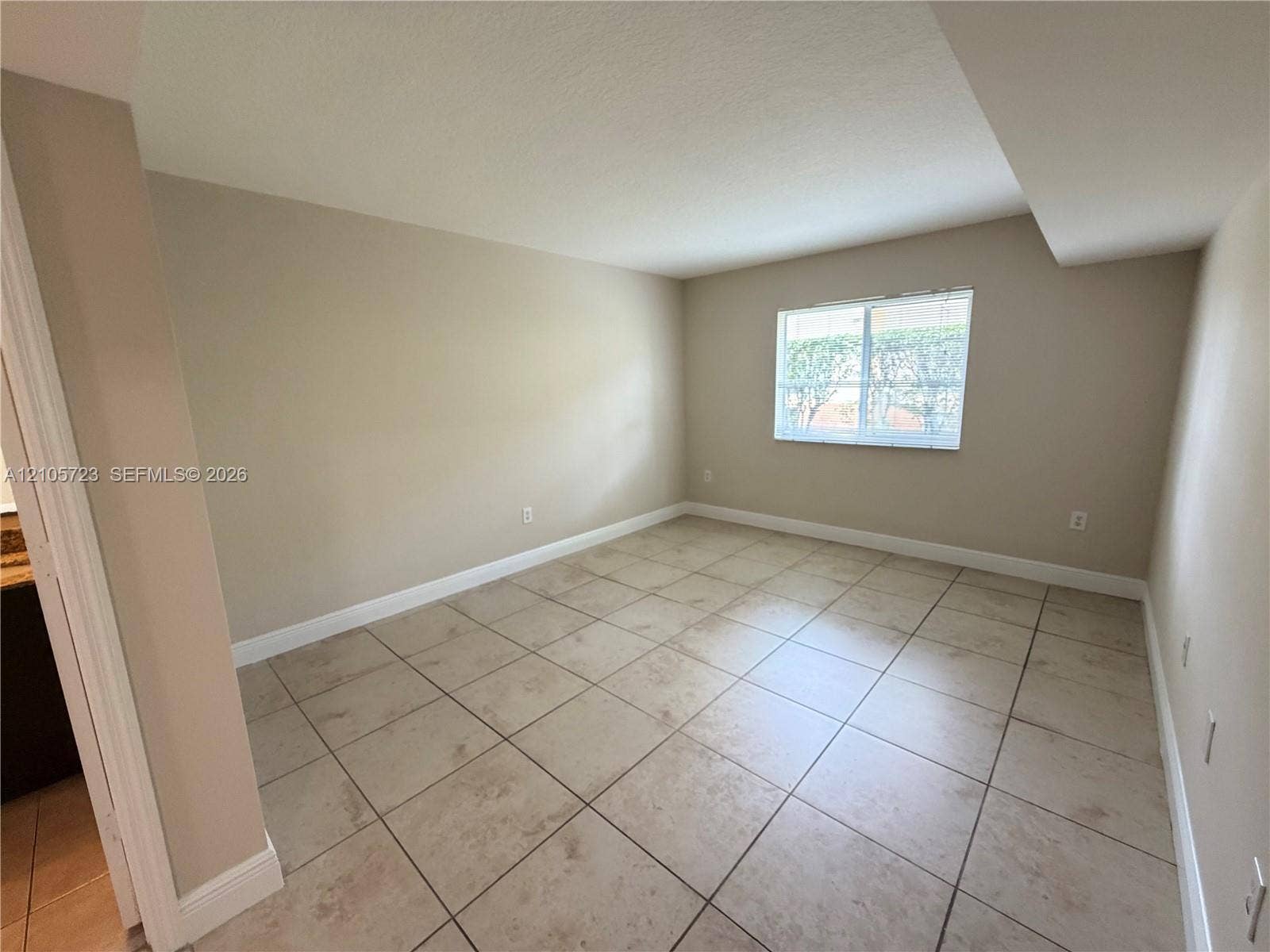 4785 SW 62nd Avenue, #102, Davie, Davie, FL 33314 Neutral-toned interior space featuring light-colored square tile flooring, smooth walls, and a single-pane window