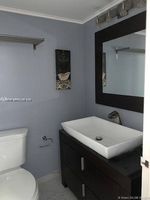 200 172nd Street, #101, Sunny Isles Beach, FL 33160 Dark wood-finish vanity featuring a white rectangular vessel sink, mounted mirror with a matching dark frame, and multi-bulb light fixture