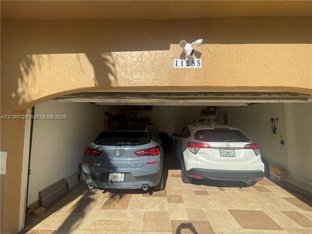 Two-car garage featuring a stucco exterior finish and tile flooring