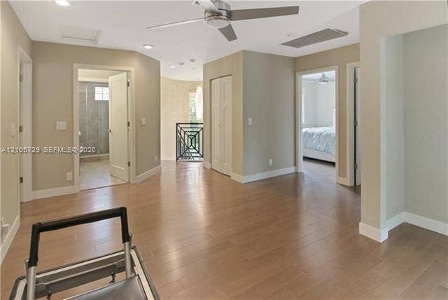 Interior space featuring wood-finish flooring, recessed lighting, a brushed metal ceiling fan, and decorative wrought iron railing