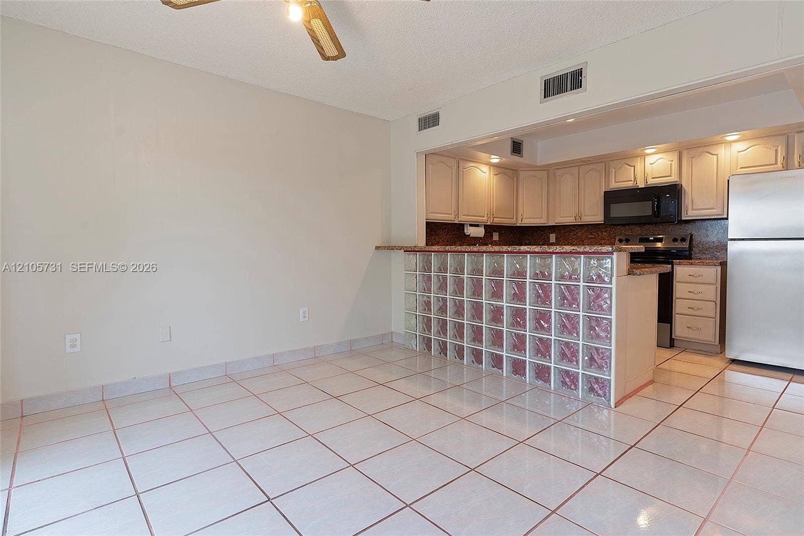 5700 SW 127th Avenue, #1404, Miami, FL 33183 Kitchen area featuring a glass block breakfast bar, ceramic tile flooring, neutral cabinetry, stone-finish countertops, and stainless steel appliances