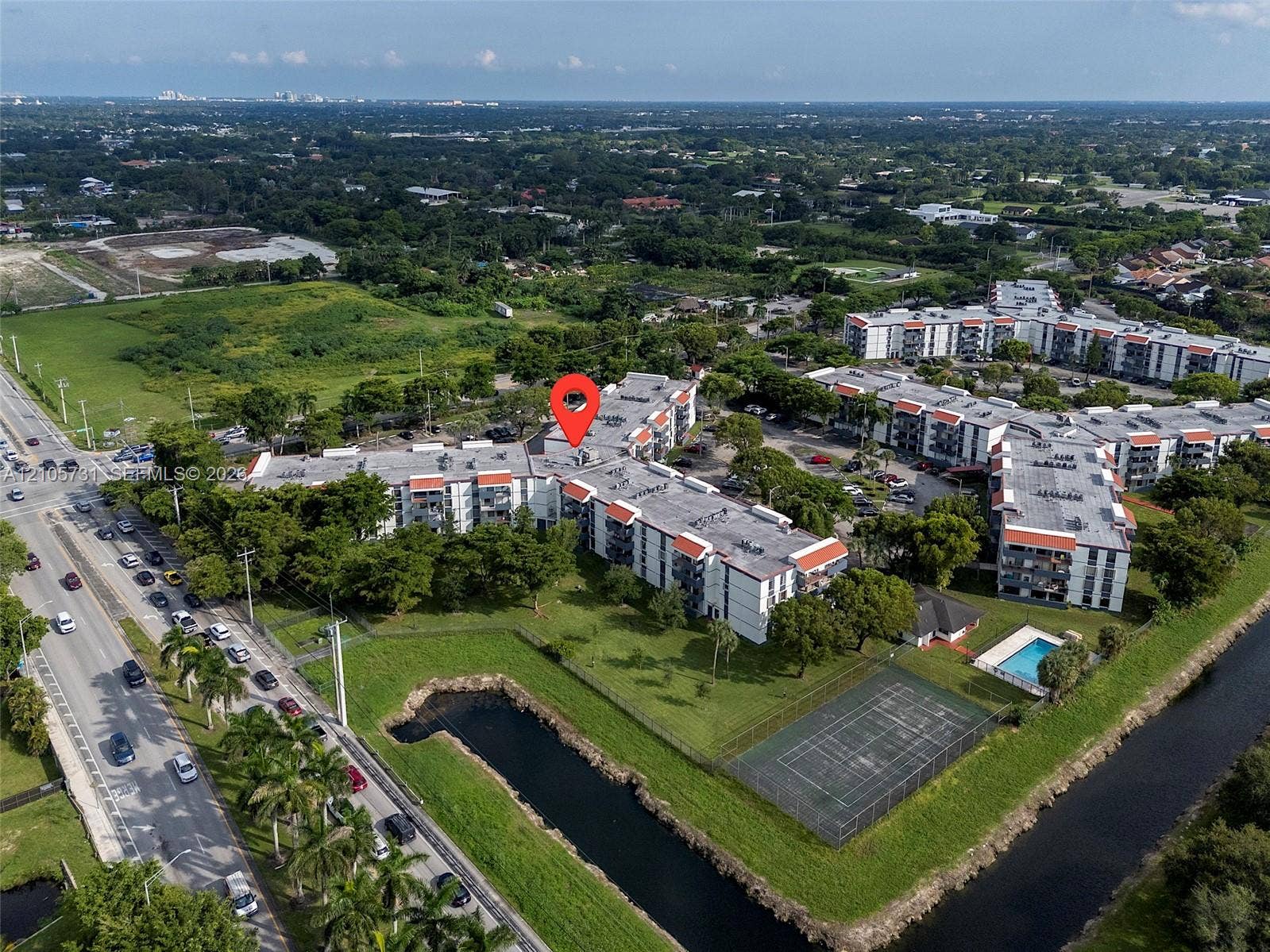 5700 SW 127th Avenue, #1404, Miami, FL 33183 Aerial perspective of multi-story residential complex featuring an outdoor swimming pool, tennis court, and manicured lawn areas