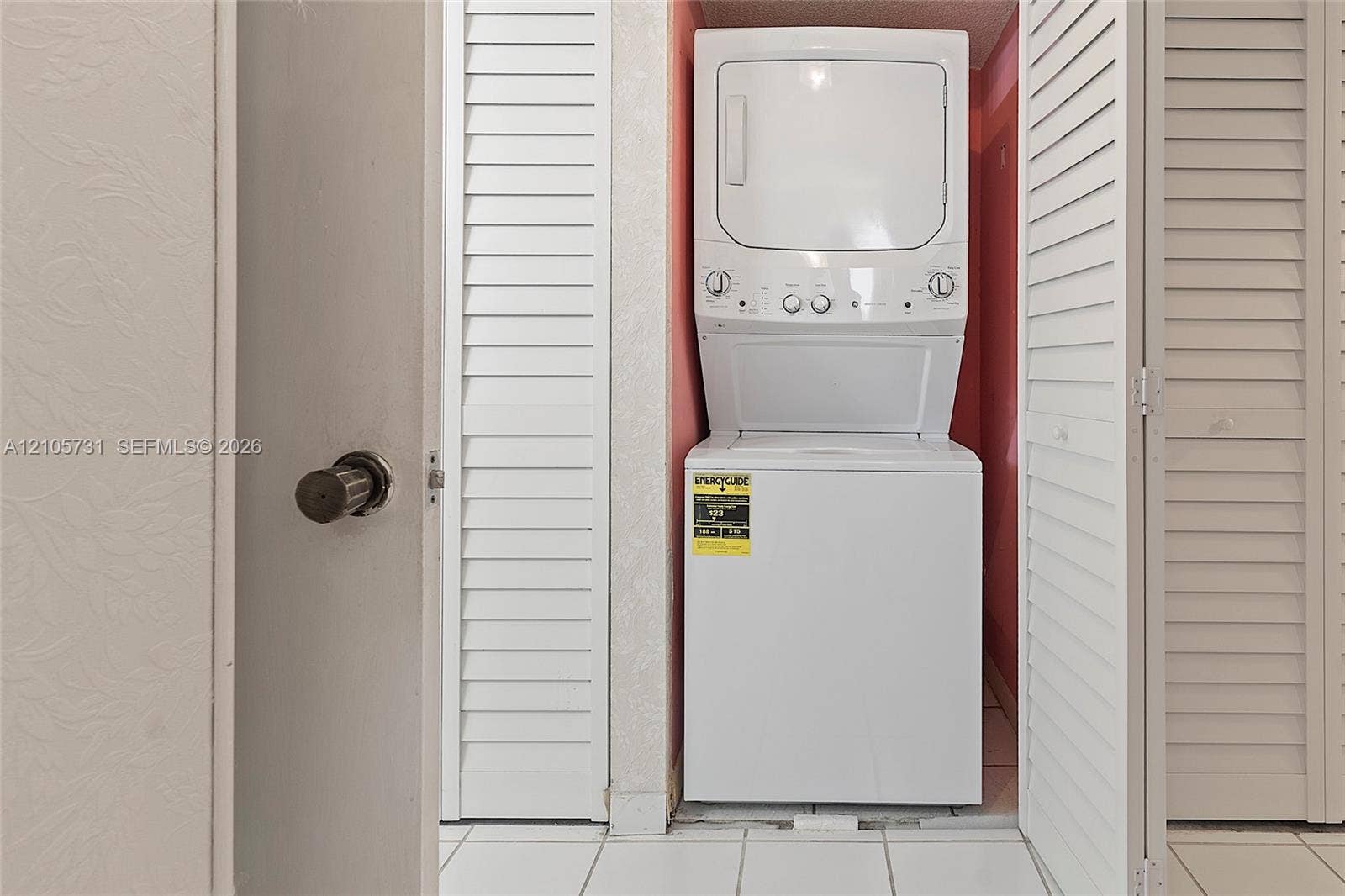 5700 SW 127th Avenue, #1404, Miami, FL 33183 Stacked laundry unit housed within a closet featuring white louvered doors and tile flooring