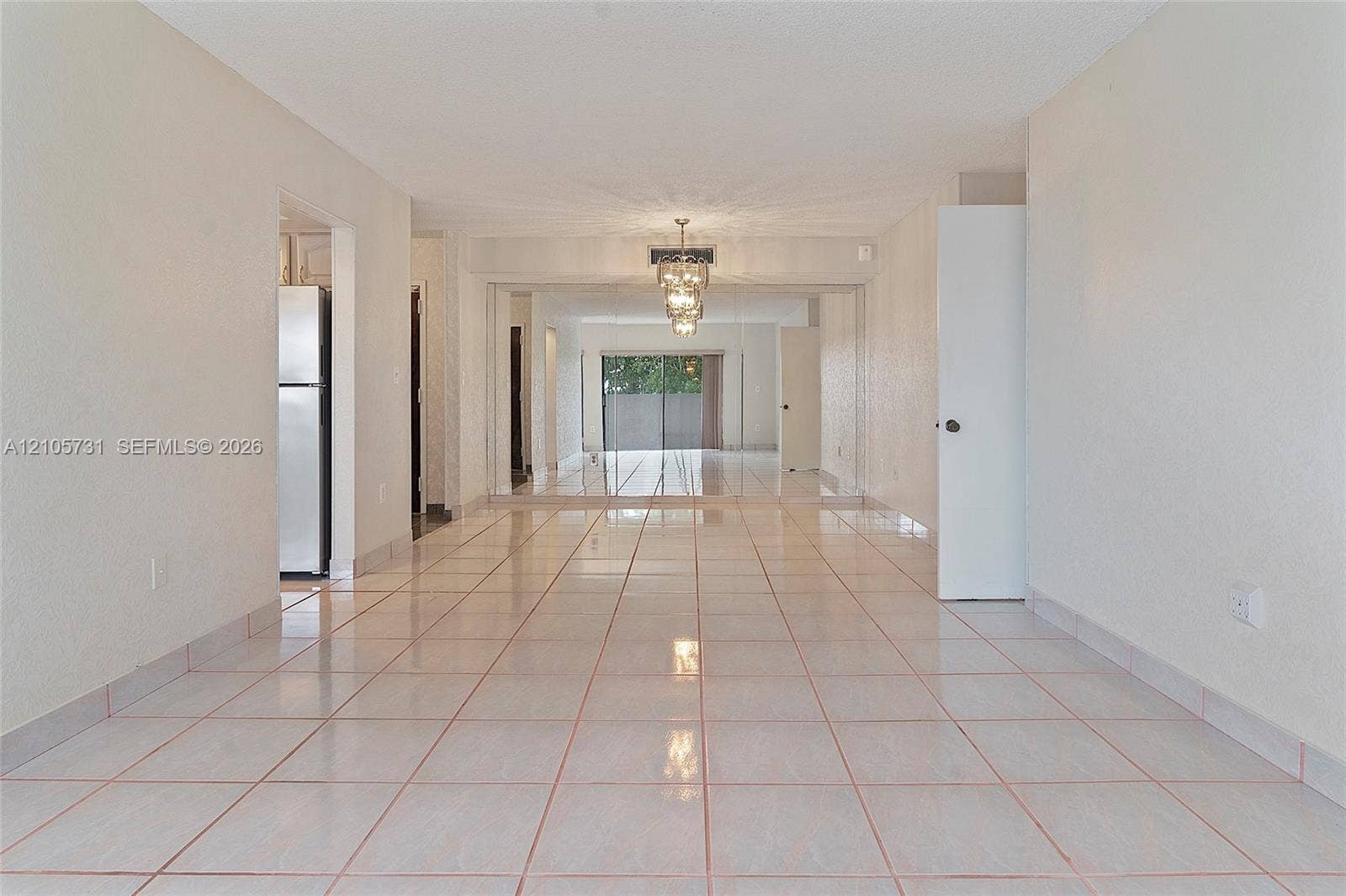 5700 SW 127th Avenue, #1404, Miami, FL 33183 Neutral tile flooring, expansive mirrored wall panels, and a tiered crystal chandelier
