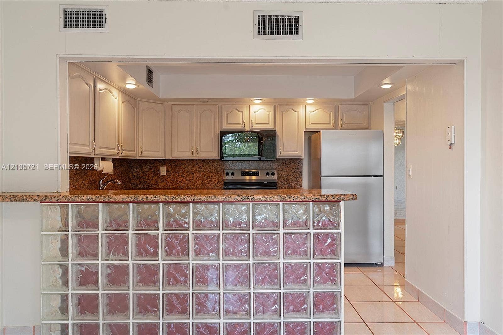 5700 SW 127th Avenue, #1404, Miami, FL 33183 Kitchen featuring white cabinetry, stone-finish countertops, stainless steel appliances, and a glass block breakfast bar
