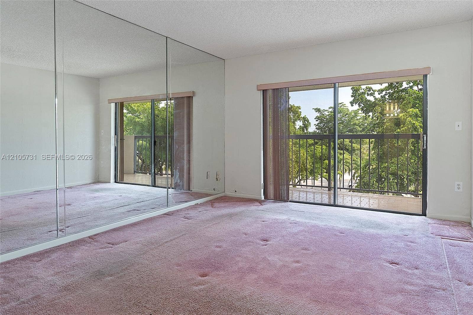 5700 SW 127th Avenue, #1404, Miami, FL 33183 Full-wall mirrored closet doors, sliding glass door with balcony access, and exterior metal railings