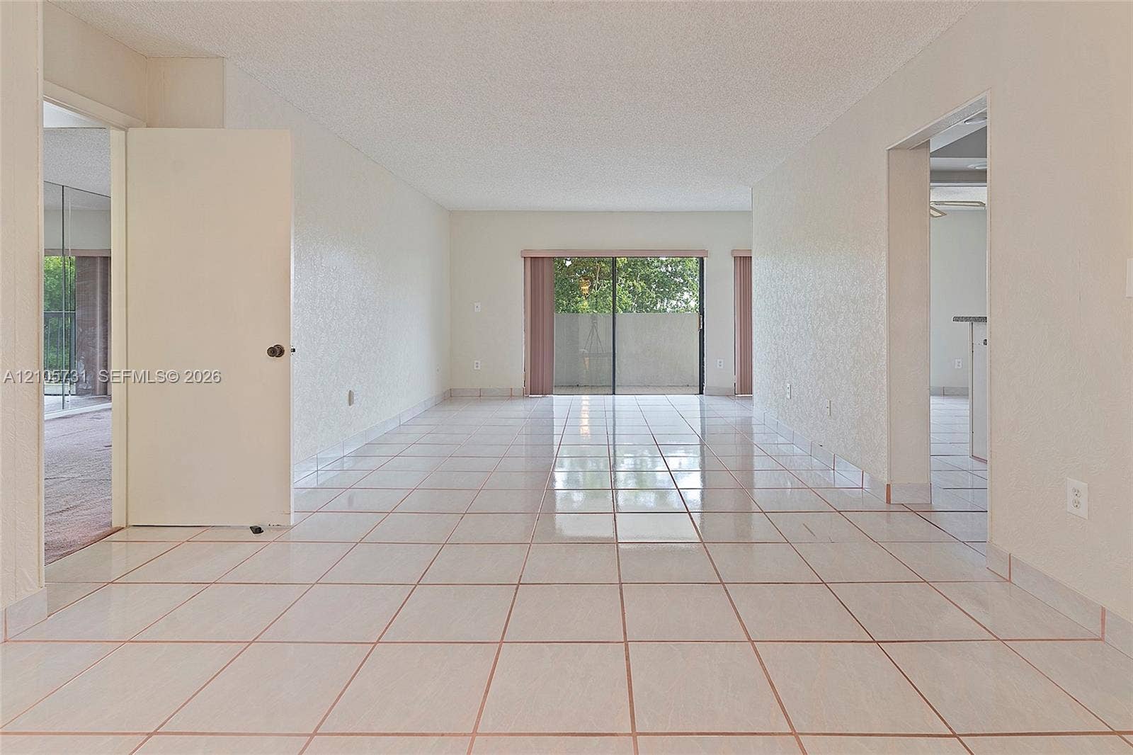 5700 SW 127th Avenue, #1404, Miami, FL 33183 Open floor plan featuring ceramic tile flooring, textured ceilings, and a sliding glass door providing external access