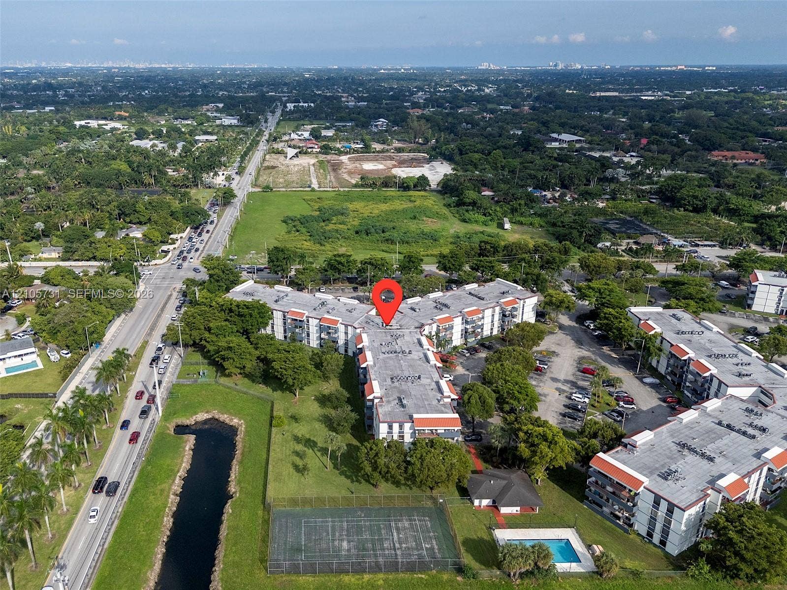 5700 SW 127th Avenue, #1404, Miami, FL 33183 Aerial view featuring multi-story residential buildings, an outdoor swimming pool, and a fenced tennis court