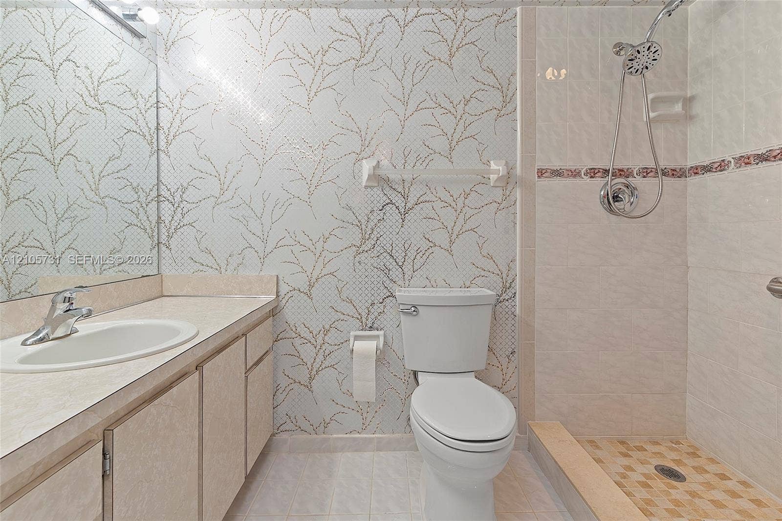 5700 SW 127th Avenue, #1404, Miami, FL 33183 Bathroom featuring a vanity with an integrated sink, patterned wall covering, floor-to-ceiling mirror, and a walk-in shower with a handheld fixture and decorative tile accent border