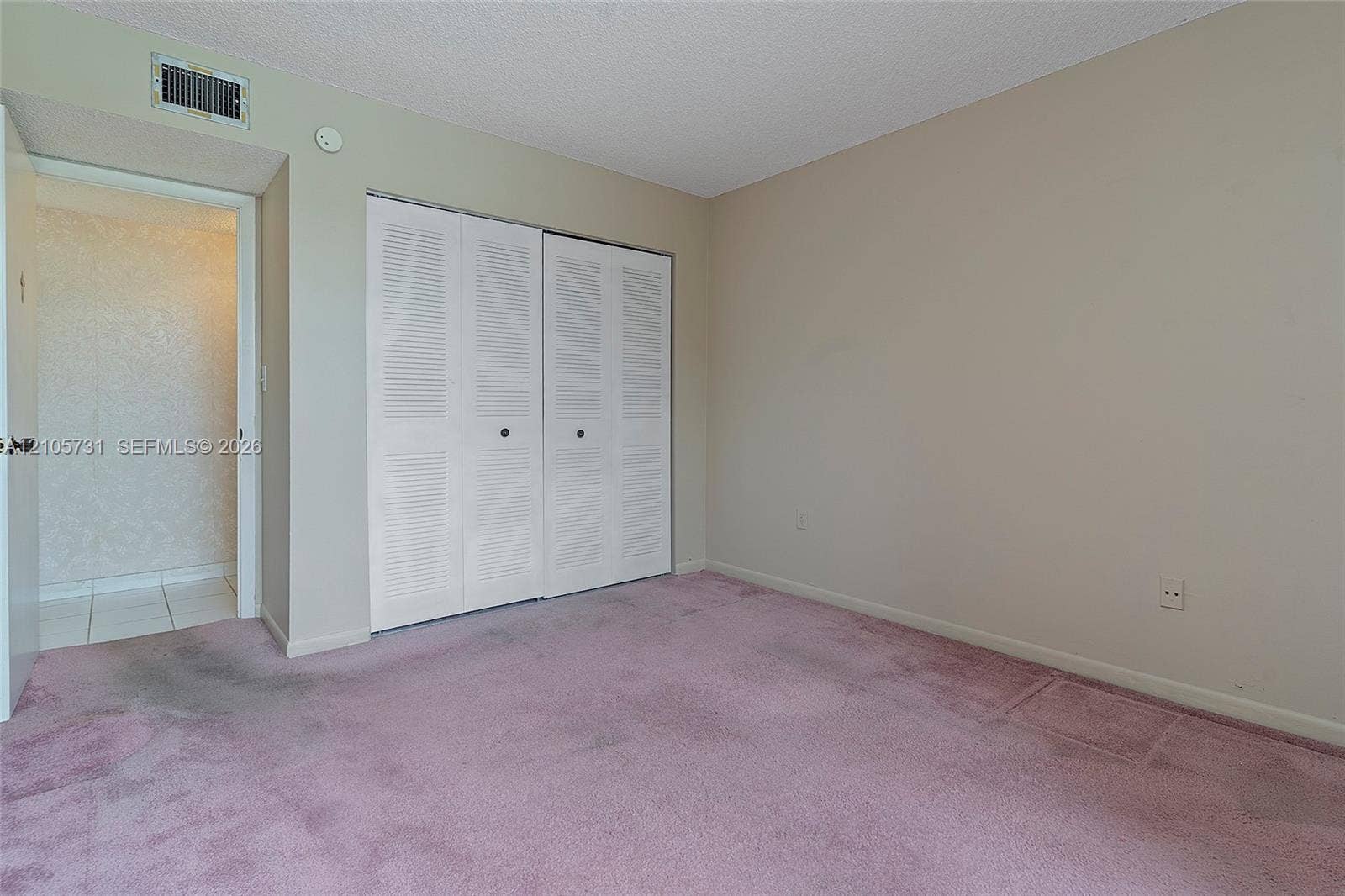 5700 SW 127th Avenue, #1404, Miami, FL 33183 Interior space featuring carpeted flooring, white louvered-style bi-fold closet doors, and neutral wall paint