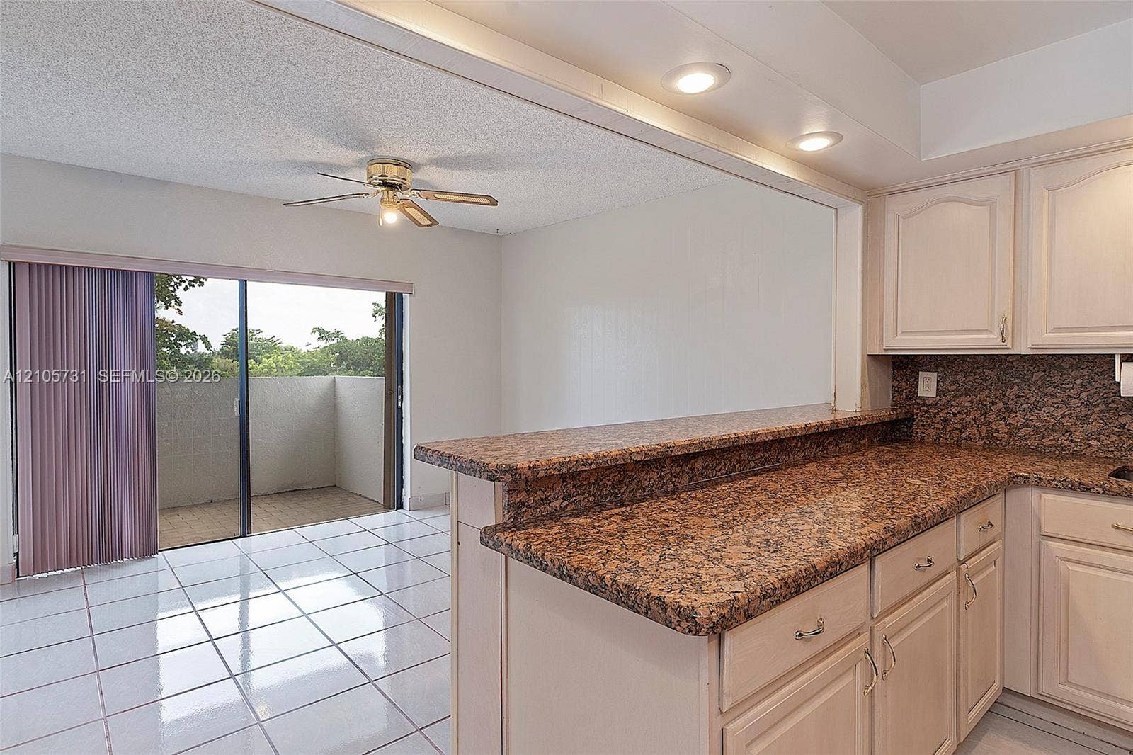 5700 SW 127th Avenue, #1404, Miami, FL 33183 Kitchen featuring cabinetry with crown molding, stone-finish countertops, recessed lighting, white tile flooring, and a sliding glass door