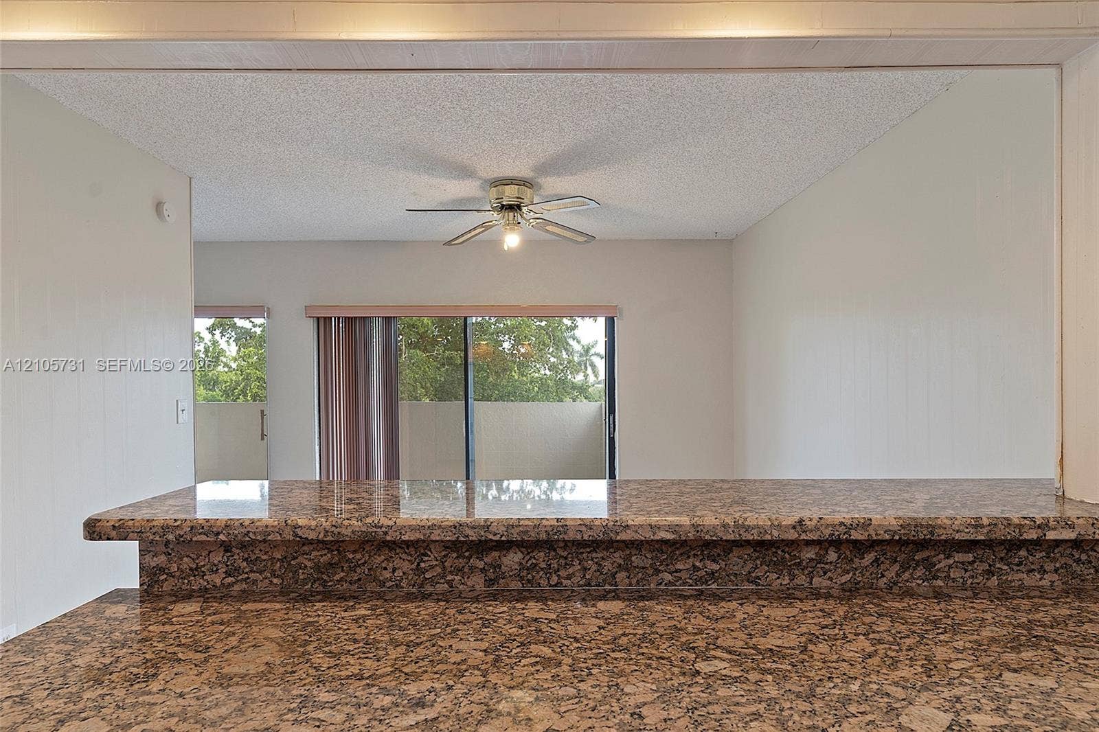 5700 SW 127th Avenue, #1404, Miami, FL 33183 Stone-surfaced breakfast bar with an extended overhang, textured ceiling finish, and ceiling-mounted fan
