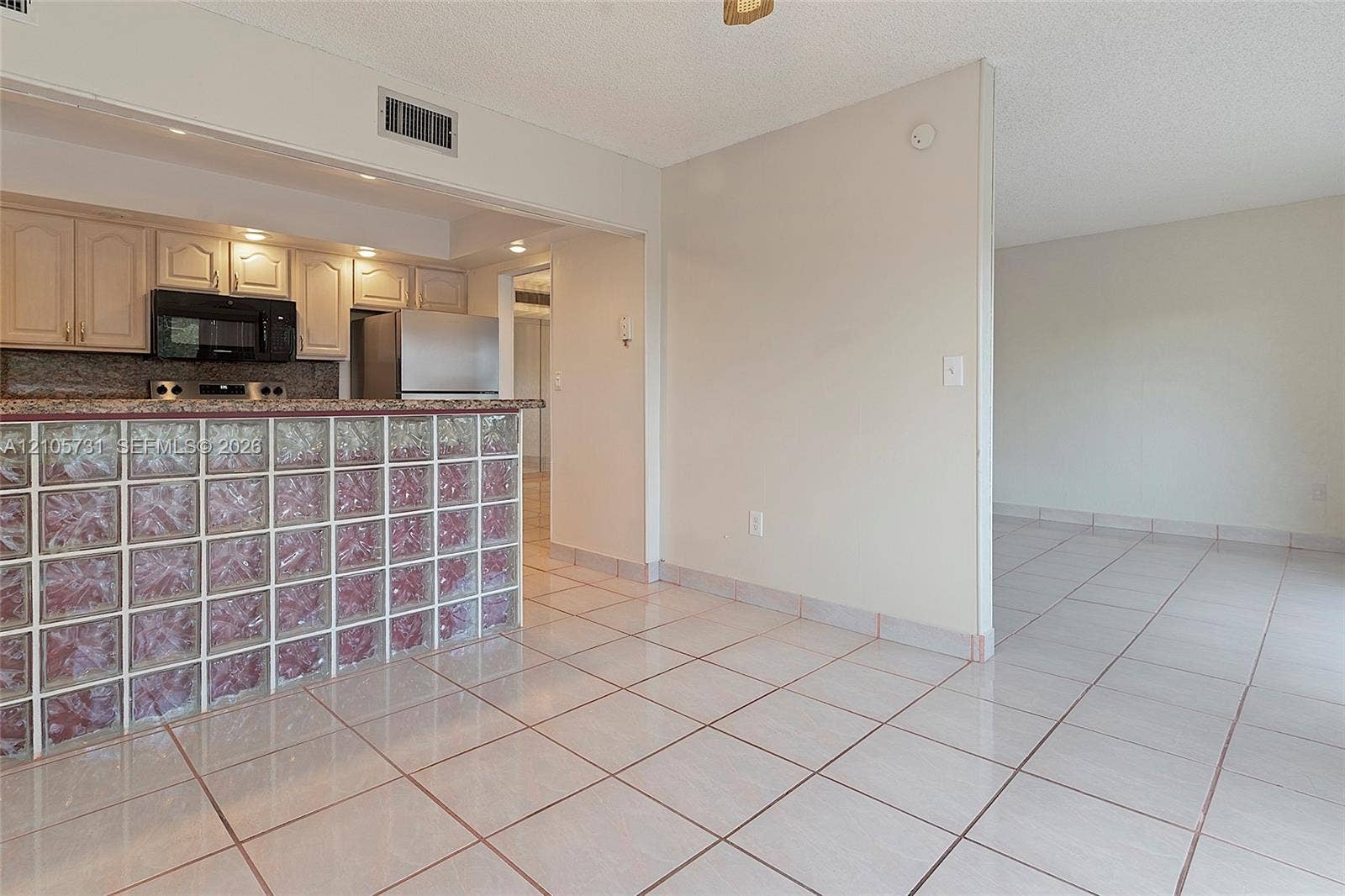 5700 SW 127th Avenue, #1404, Miami, FL 33183 Kitchen featuring a glass block peninsula, stone-surfaced countertops, custom cabinetry, and ceramic tile flooring