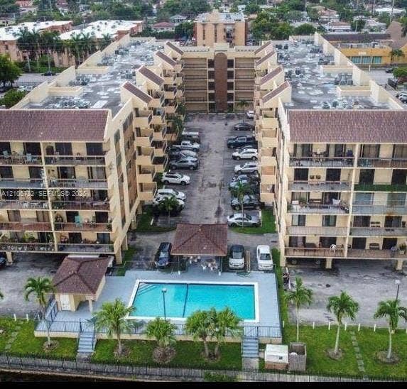 5249 NW 7th Street, #219, Miami, Miami, FL 33126 Aerial perspective of a multi-story residential complex featuring multiple private balconies, a ground-level swimming pool, a covered poolside pavilion, and paved surface parking