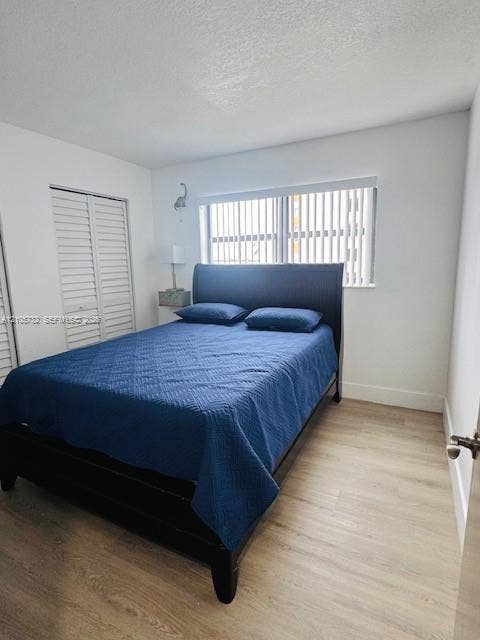 5249 NW 7th Street, #219, Miami, Miami, FL 33126 Neutral wall palette with wood-finish flooring, louvered-style closet doors, and a horizontal window with vertical blinds