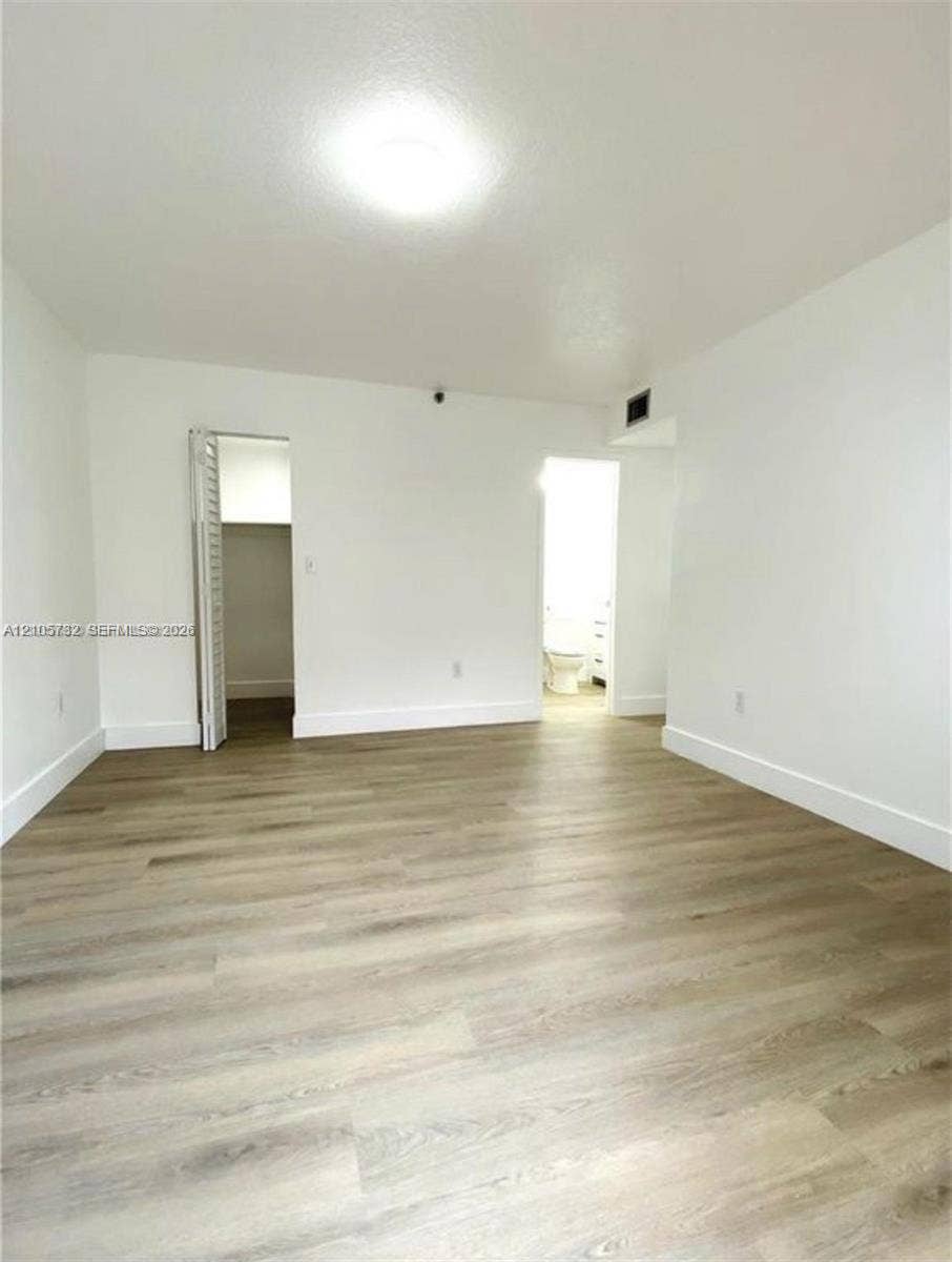 5249 NW 7th Street, #219, Miami, Miami, FL 33126 Interior space featuring wood-finish flooring, white walls, and a recessed closet with bi-fold doors