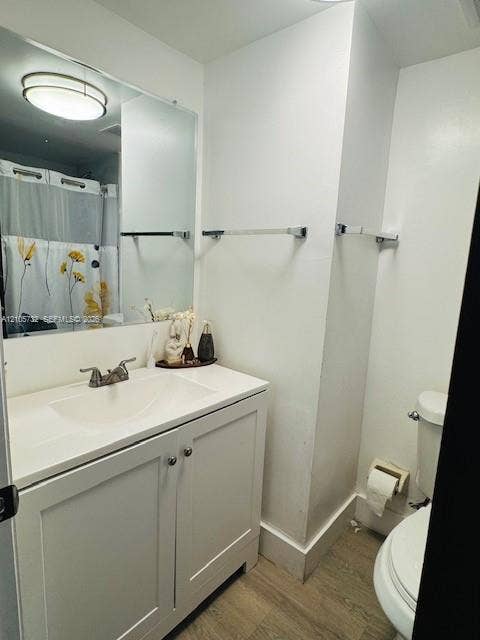 5249 NW 7th Street, #219, Miami, Miami, FL 33126 Bathroom featuring a white vanity cabinet with a integrated sink, large wall-mounted mirror, brushed-nickel hardware, and wood-finish flooring