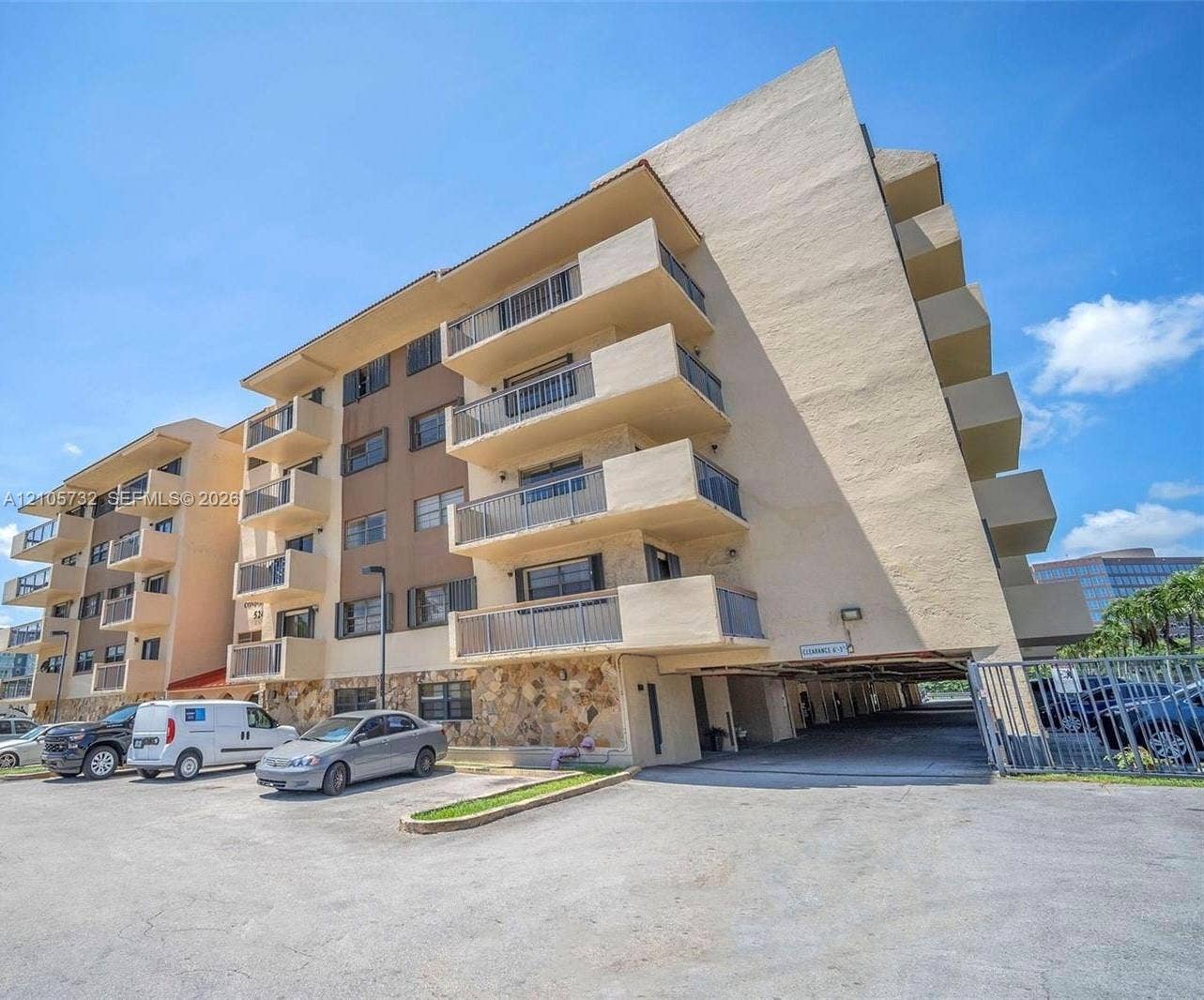 5249 NW 7th Street, #219, Miami, Miami, FL 33126 Multi-story exterior featuring stone veneer accents, private balconies with metal railings, and a covered ground-level parking area
