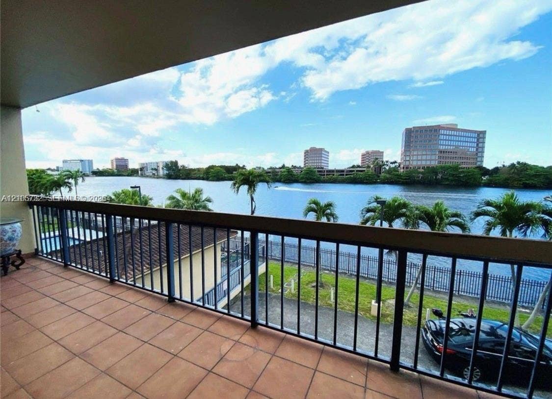 5249 NW 7th Street, #219, Miami, Miami, FL 33126 Covered terrace with terracotta-style tile flooring and a dark metal railing overlooking a waterway