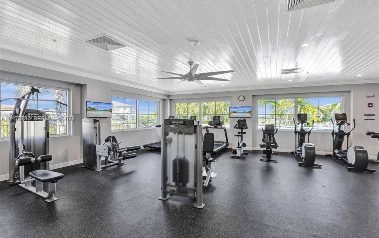 Fitness center featuring high-gloss tongue-and-groove ceilings, recessed lighting, expansive multi-pane windows, and durable rubberized flooring
