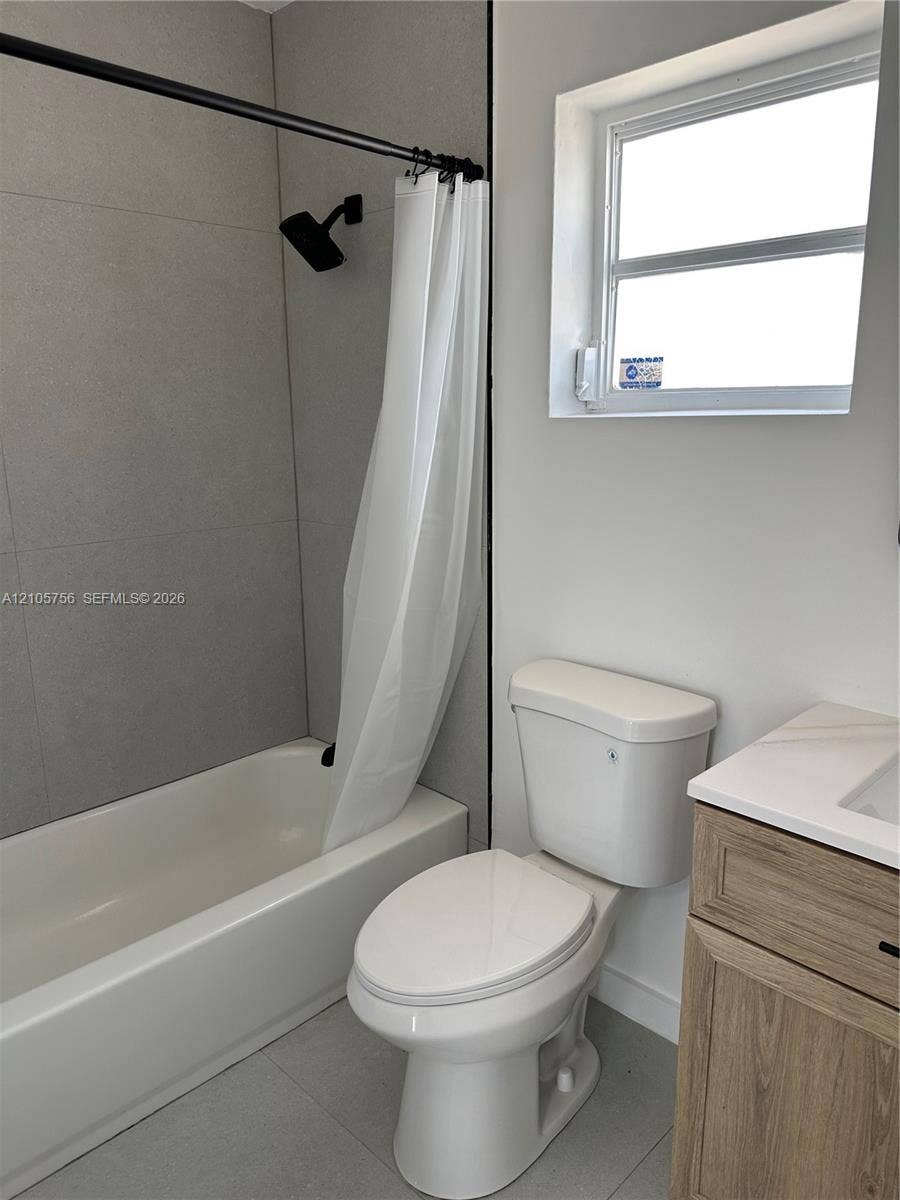 137 SE 2nd Avenue, #A, Hallandale Beach, Hallandale Beach, FL 33009 Bathroom featuring large-format grey tile surround, matte black shower fixture, wood-finish vanity with countertop basin, and neutral wall tones
