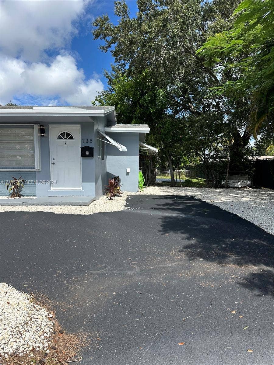 137 SE 2nd Avenue, #A, Hallandale Beach, Hallandale Beach, FL 33009 Exterior facade featuring light-colored siding, asphalt driveway, stone ground cover, and metal window awnings