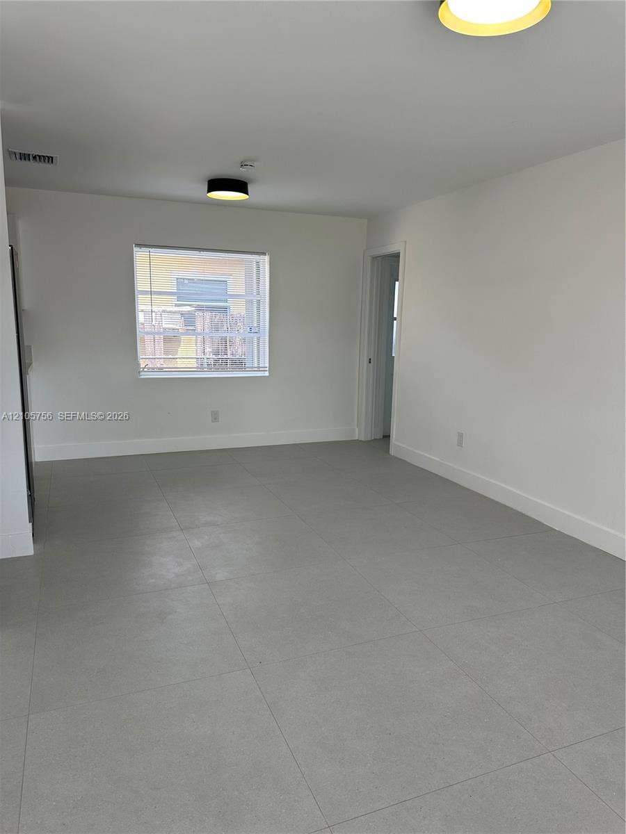 137 SE 2nd Avenue, #A, Hallandale Beach, Hallandale Beach, FL 33009 Neutral-toned room featuring large-format ceramic tile flooring, clean white walls, and contemporary flush-mount ceiling lighting