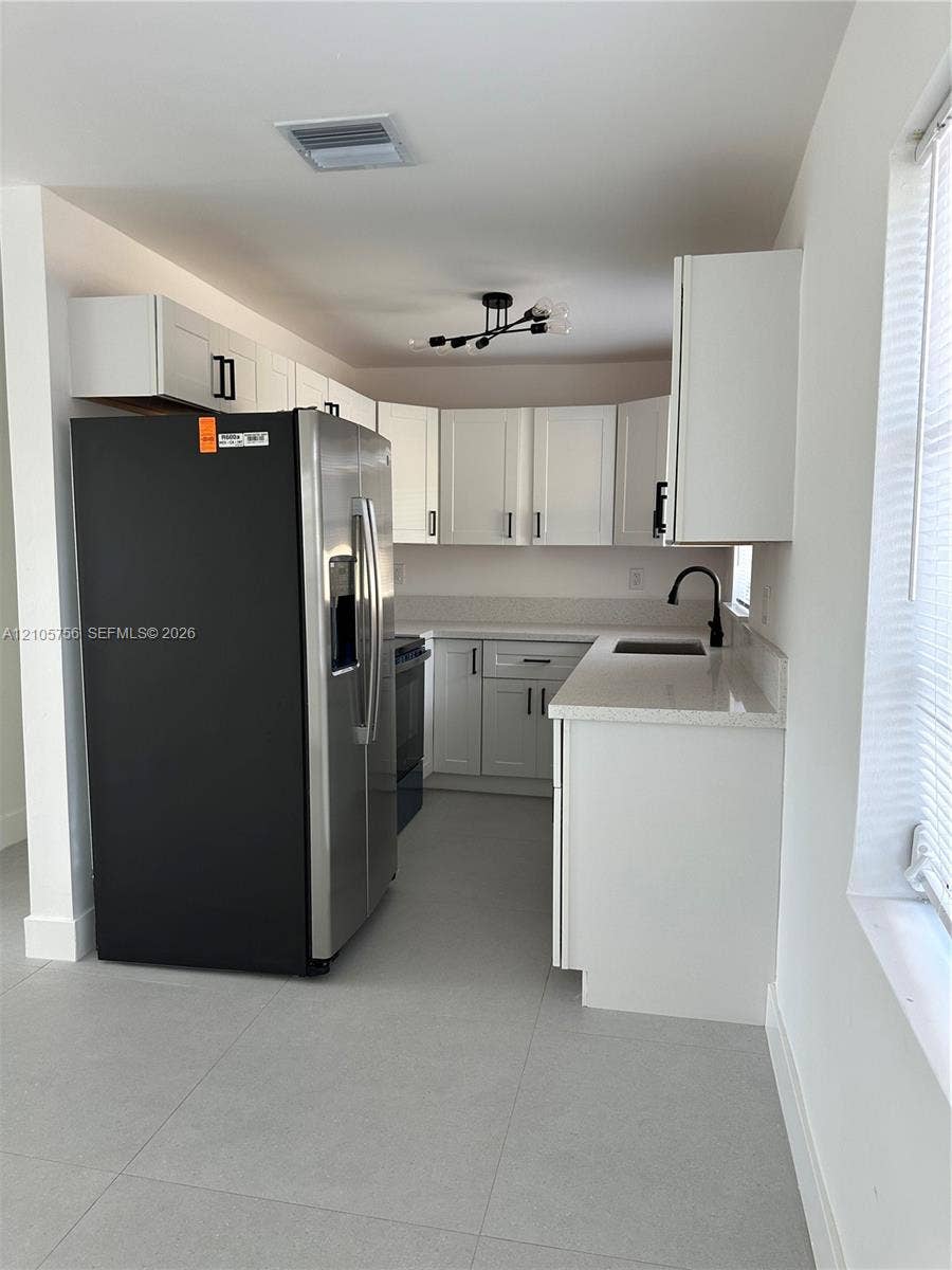 137 SE 2nd Avenue, #A, Hallandale Beach, Hallandale Beach, FL 33009 Kitchen featuring white shaker-style cabinetry, light-toned stone-surface countertops, stainless steel side-by-side refrigerator, matte black hardware, and tile flooring