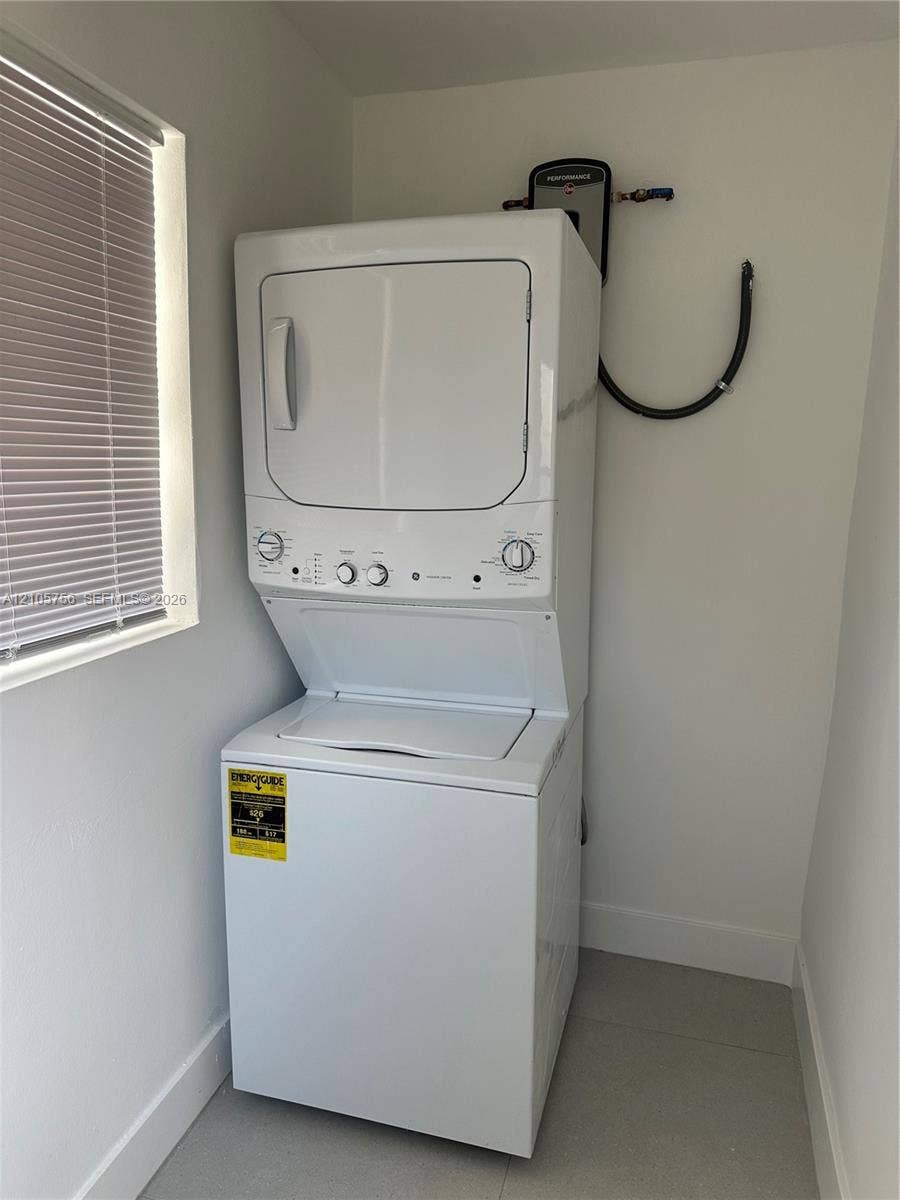 137 SE 2nd Avenue, #A, Hallandale Beach, Hallandale Beach, FL 33009 Stacked white laundry center featuring a top-load washer, a front-load dryer, and a tankless water heater