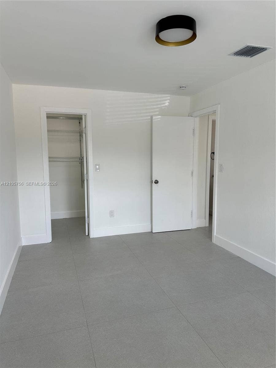 137 SE 2nd Avenue, #A, Hallandale Beach, Hallandale Beach, FL 33009 Neutral-toned ceramic tile flooring, clean white wall finishes, and a contemporary flush-mount ceiling fixture with metallic trim
