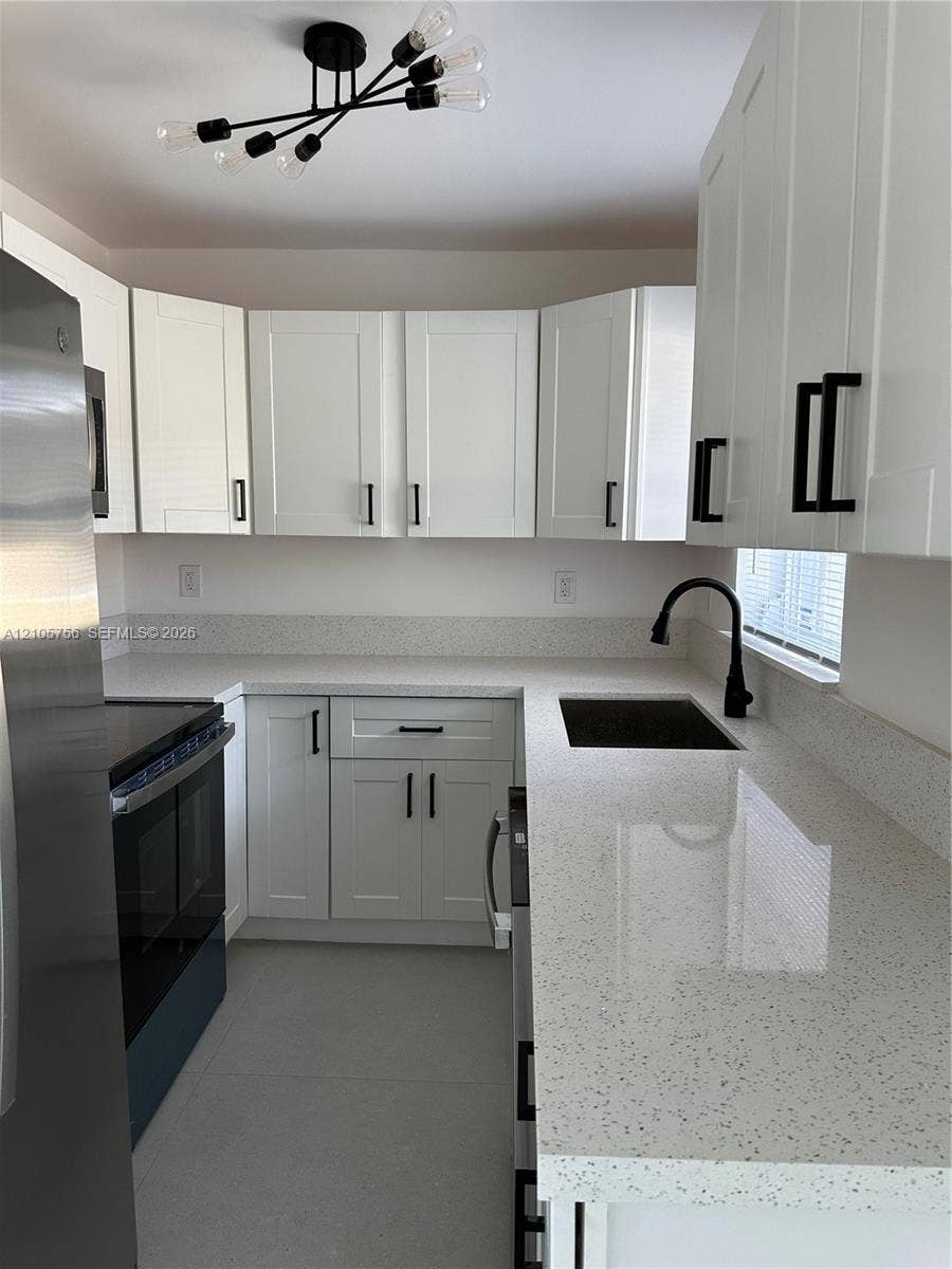 137 SE 2nd Avenue, #A, Hallandale Beach, Hallandale Beach, FL 33009 Kitchen featuring white shaker-style cabinetry, solid-surface countertops, a matte black faucet, and modern multi-arm ceiling lighting