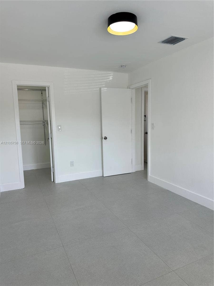 137 SE 2nd Avenue, #A, Hallandale Beach, Hallandale Beach, FL 33009 Neutral interior featuring large-format grey tile flooring, flush-mount circular lighting with a metallic rim, and built-in closet shelving