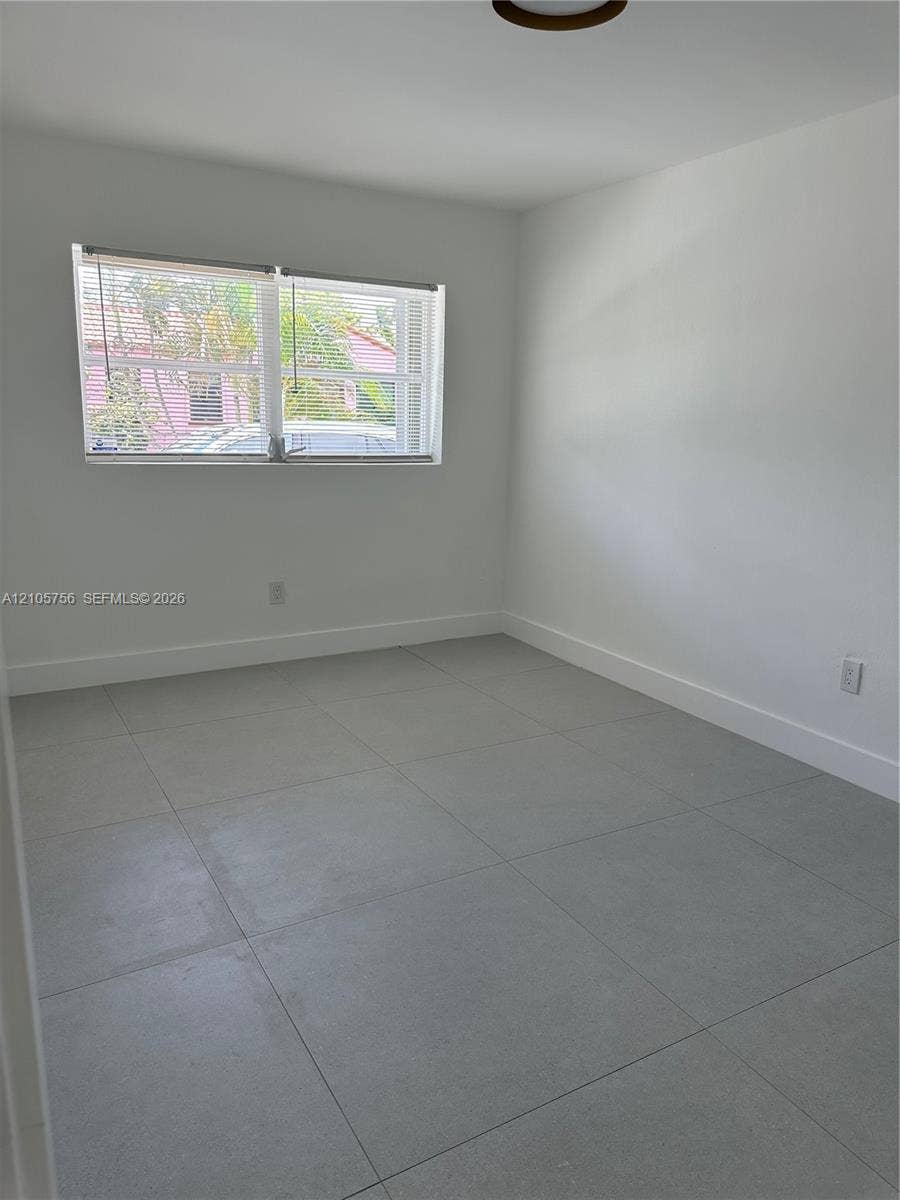 137 SE 2nd Avenue, #A, Hallandale Beach, Hallandale Beach, FL 33009 Neutral-toned interior featuring large-format ceramic floor tiles, smooth white walls, and a multi-pane horizontal window