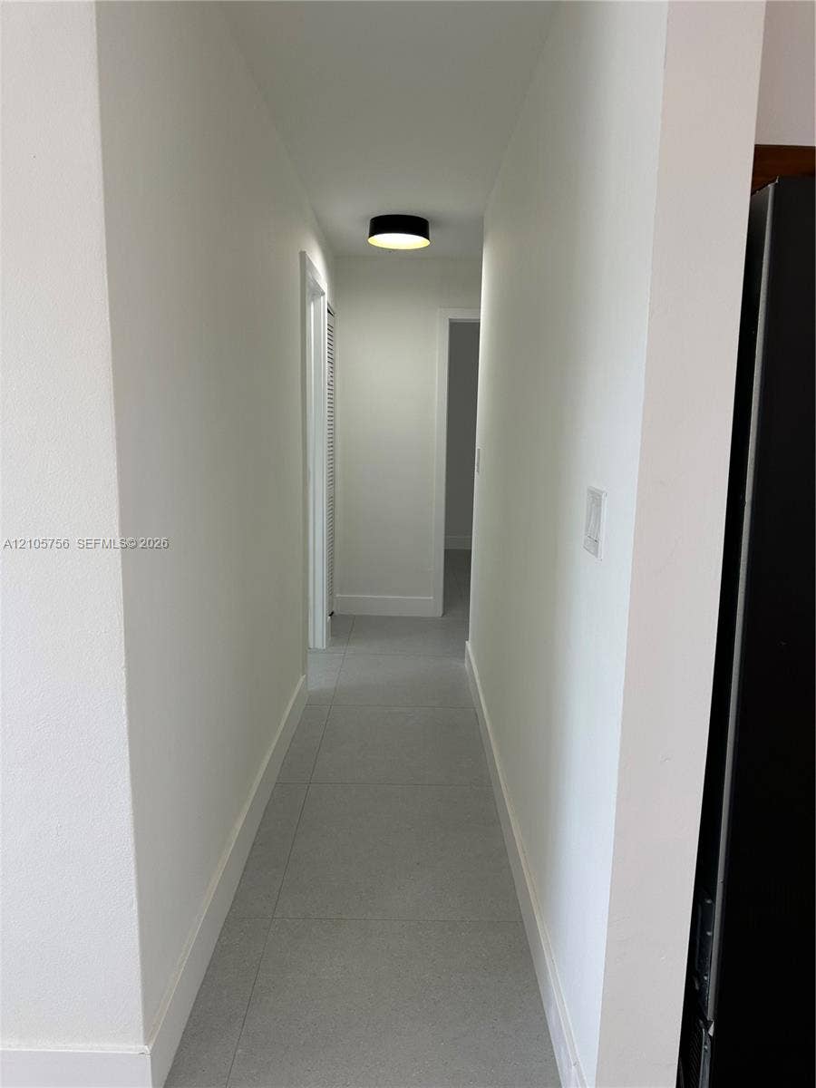 137 SE 2nd Avenue, #A, Hallandale Beach, Hallandale Beach, FL 33009 Hallway featuring large-format tile flooring, neutral wall paint, and a modern circular flush-mount ceiling fixture