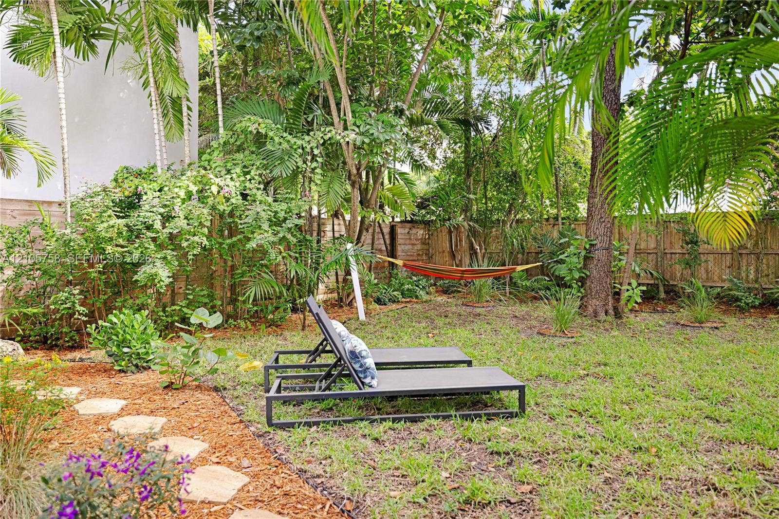 668 NE 70th Street, Miami, FL 33138 Private backyard featuring mature landscaping, natural stone pavers, and perimeter wood fencing