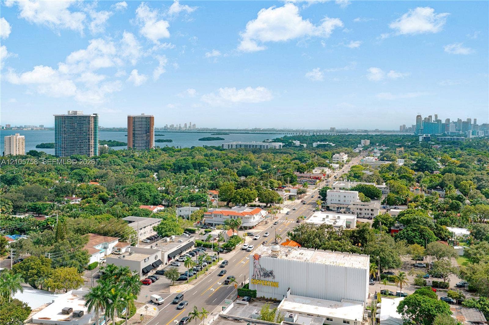 668 NE 70th Street, Miami, FL 33138 Aerial perspective of coastal surroundings featuring expansive water frontage, high-rise urban skyline, dense canopy of mature trees, and arterial thoroughfares