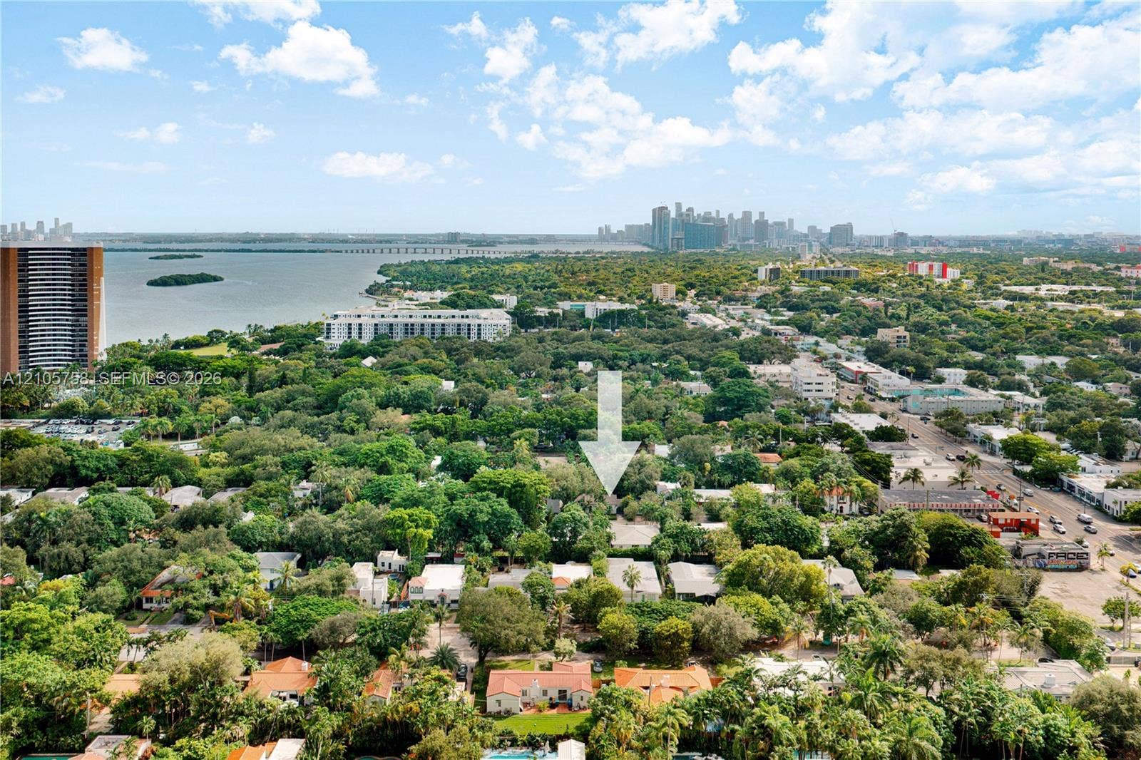 668 NE 70th Street, Miami, FL 33138 Aerial perspective of a tree-lined residential area featuring a coastal shoreline and city skyline
