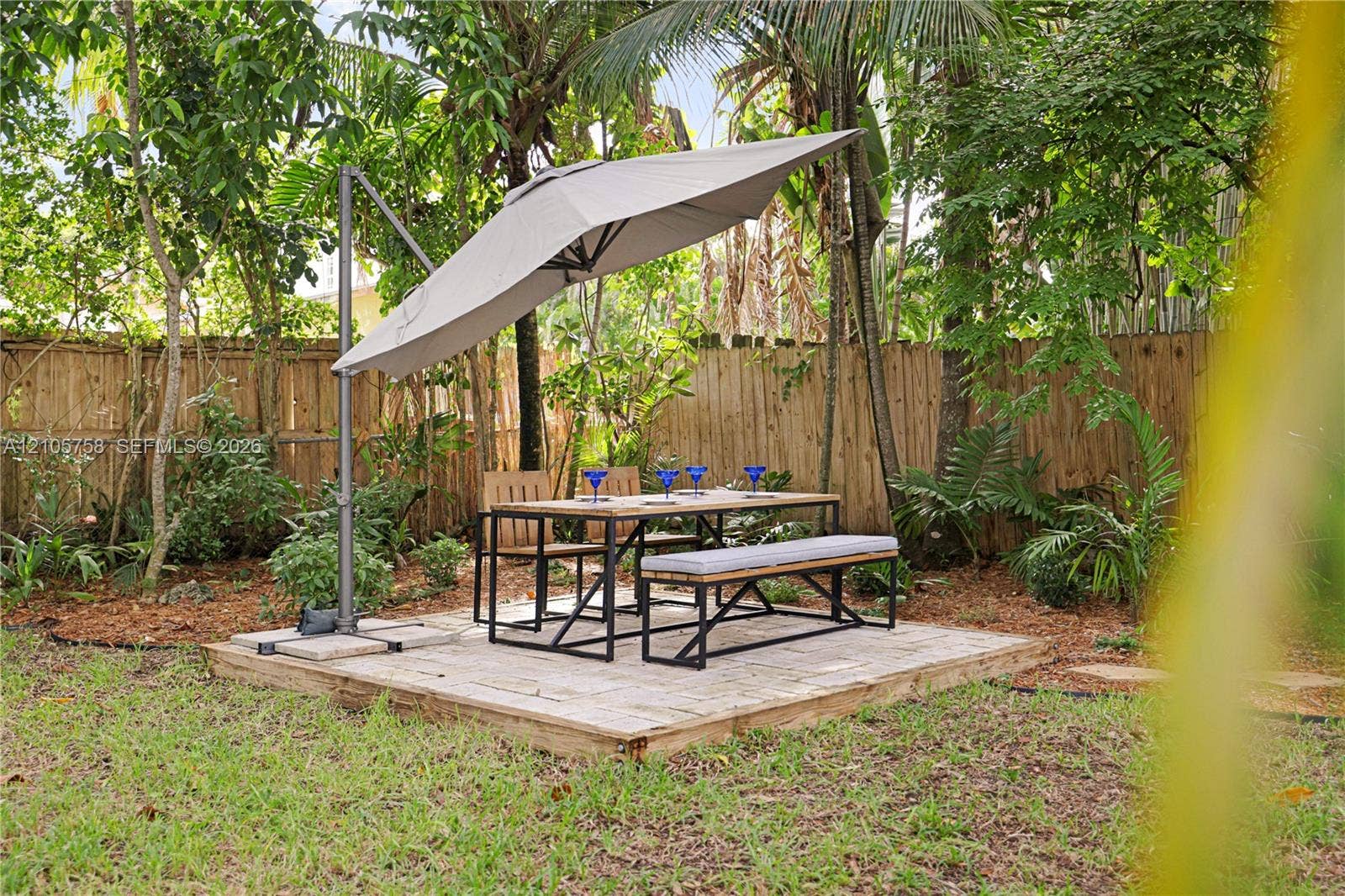 668 NE 70th Street, Miami, FL 33138 Backyard area featuring a raised wood deck, wood privacy fencing, and established perimeter landscaping