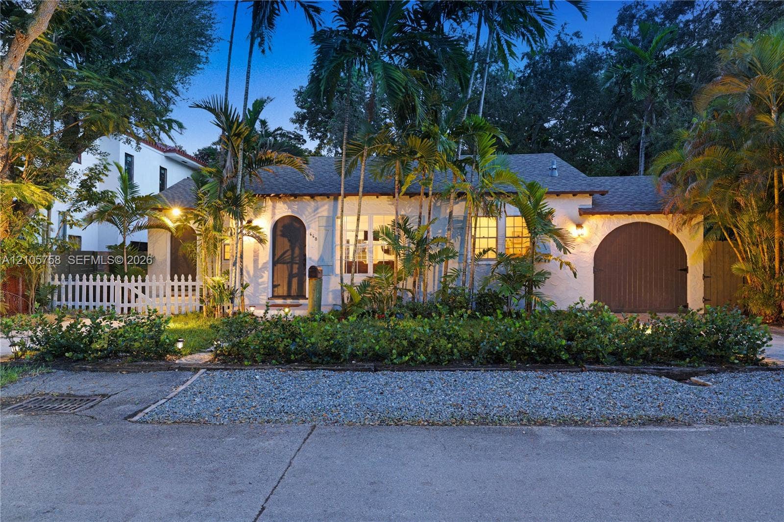 668 NE 70th Street, Miami, FL 33138 Single-story exterior featuring a textured stucco facade, arched entryway, and an attached rounded garage door