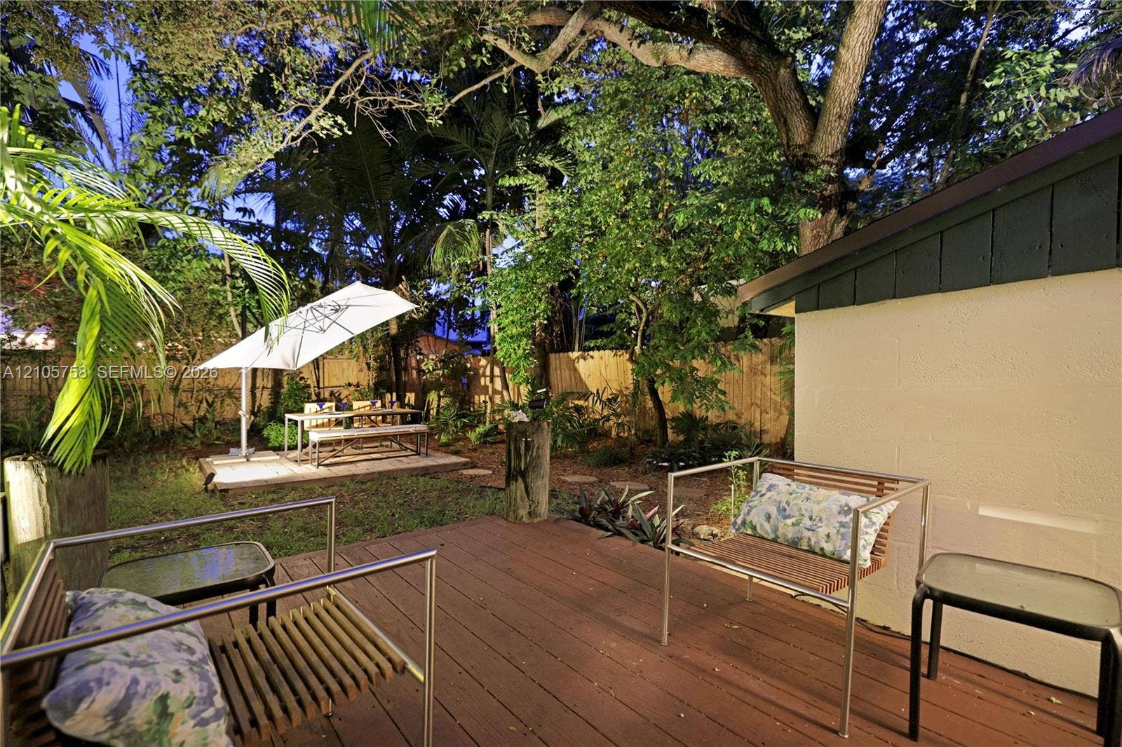 668 NE 70th Street, Miami, FL 33138 Outdoor deck featuring wood-finish decking and perimeter fencing, surrounded by mature trees and landscaped grounds
